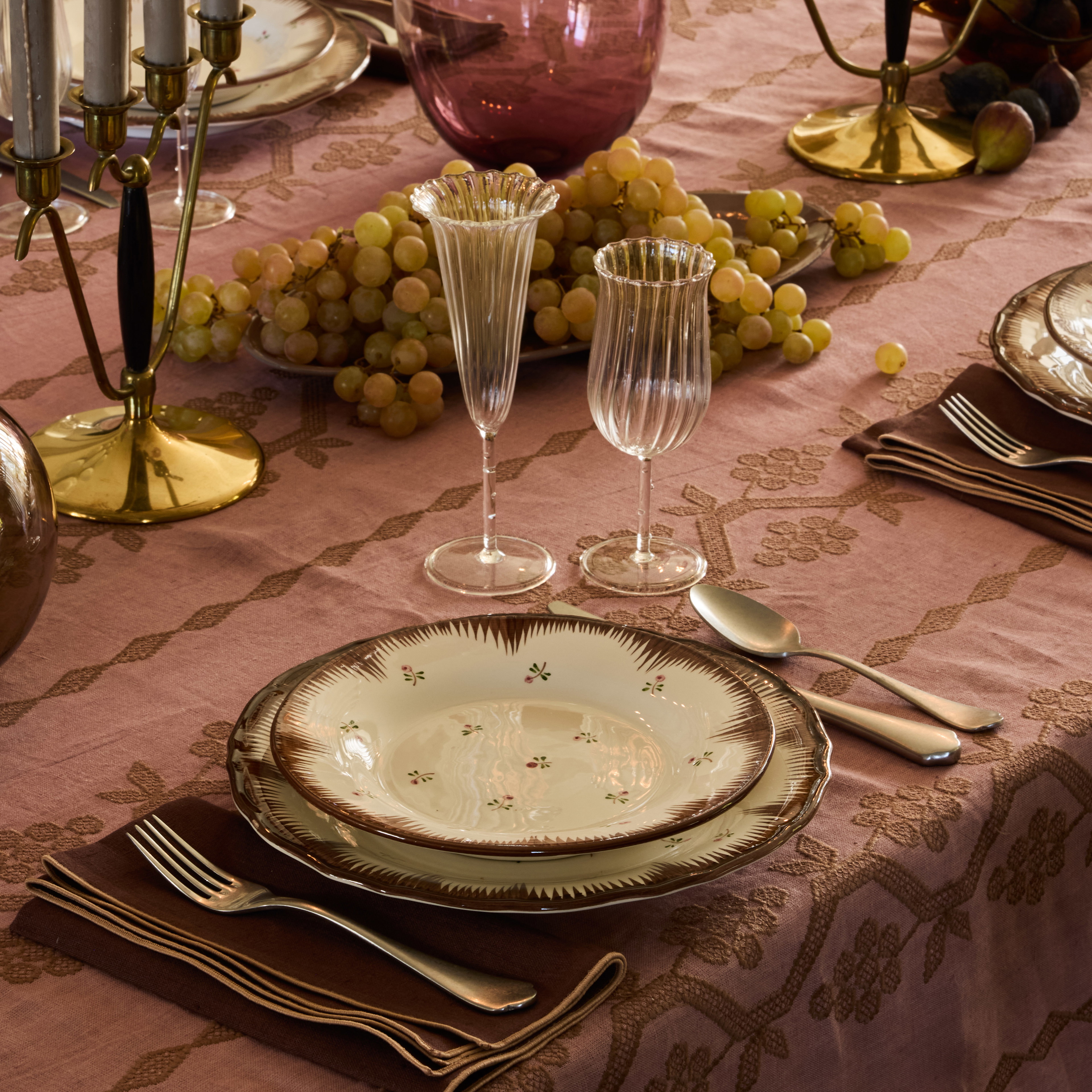 a table set with plates, silverware and wine glasses