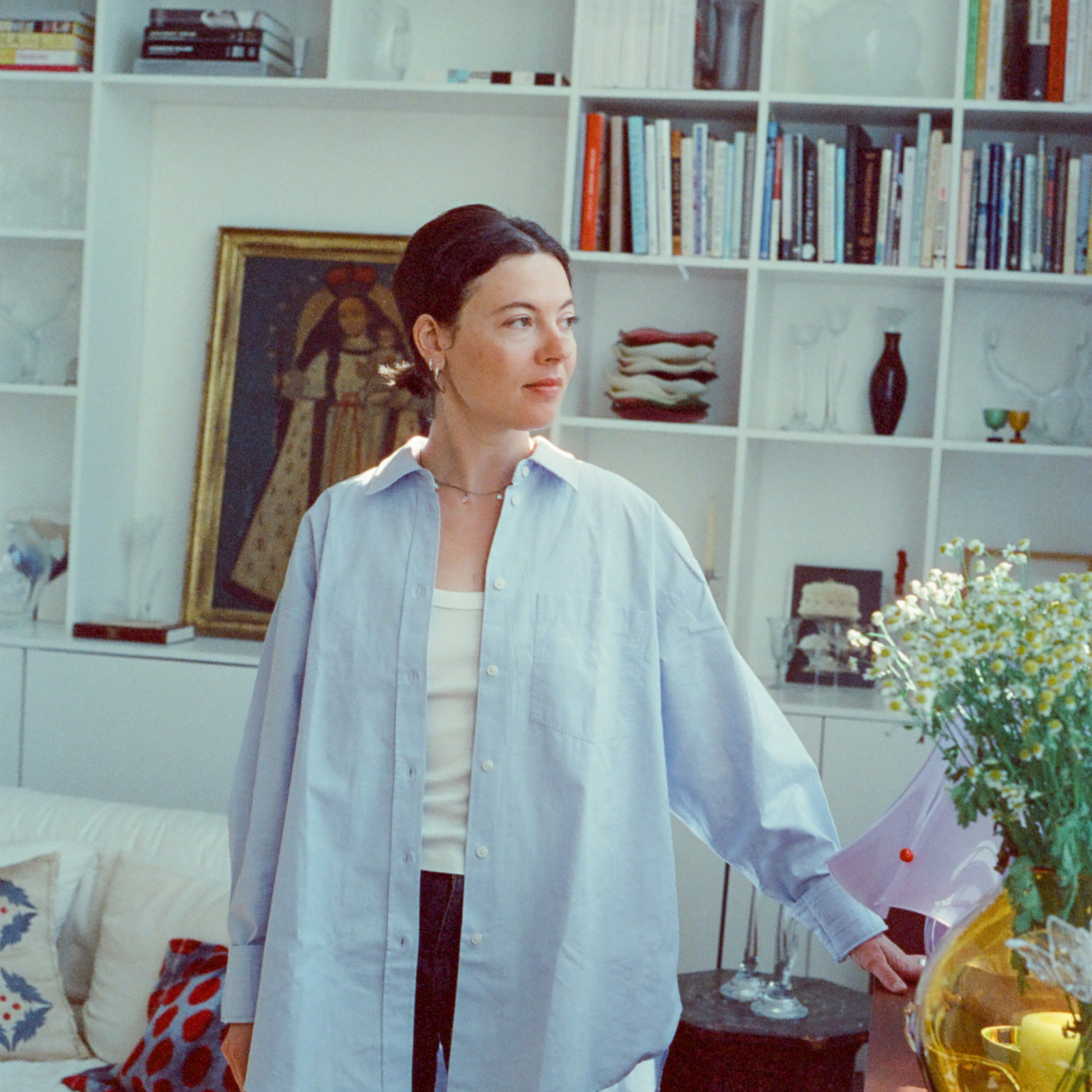 a woman standing in a living room next to a book shelf