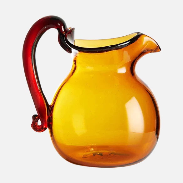 a yellow glass pitcher with a red handle