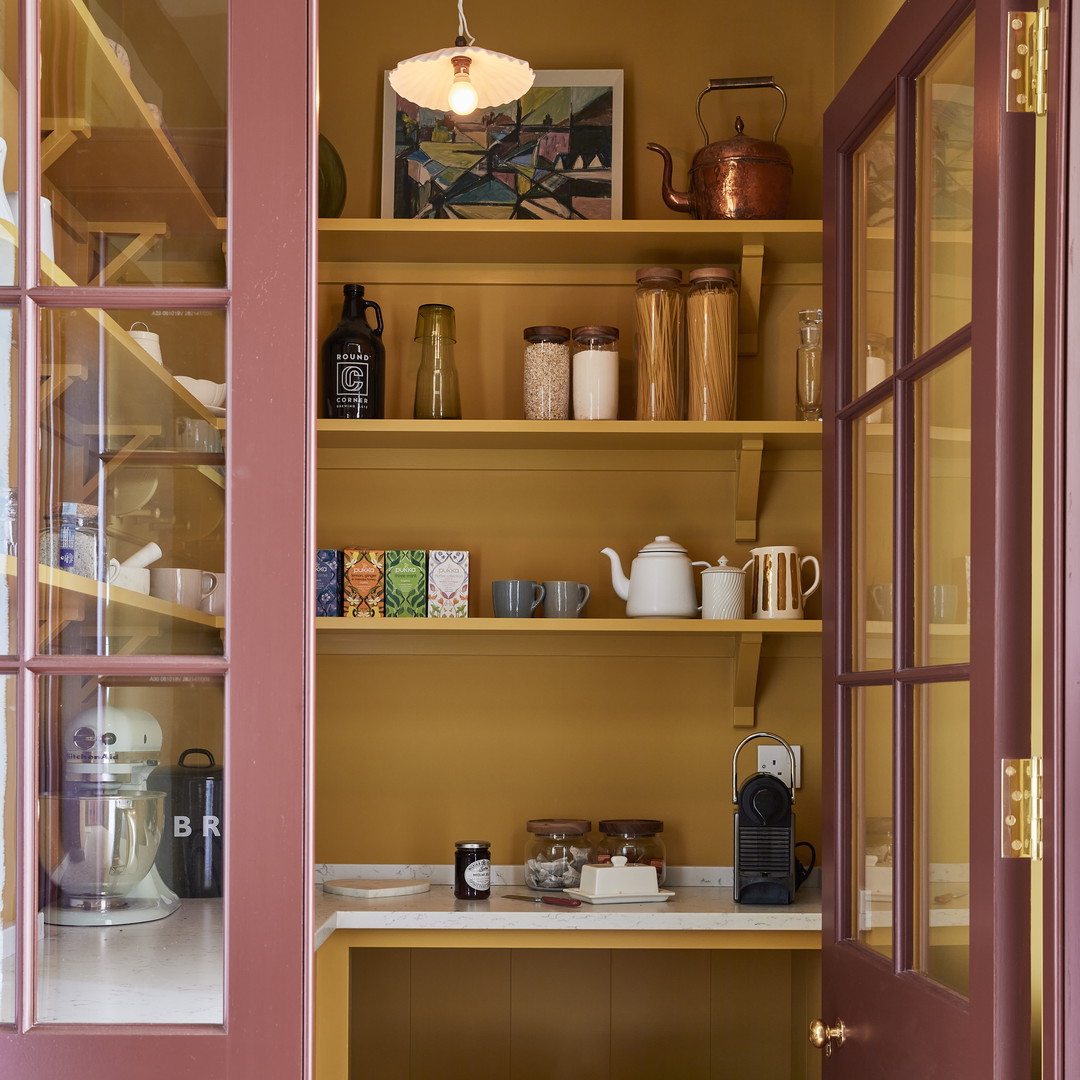 a kitchen with a pink door and shelves filled with dishes