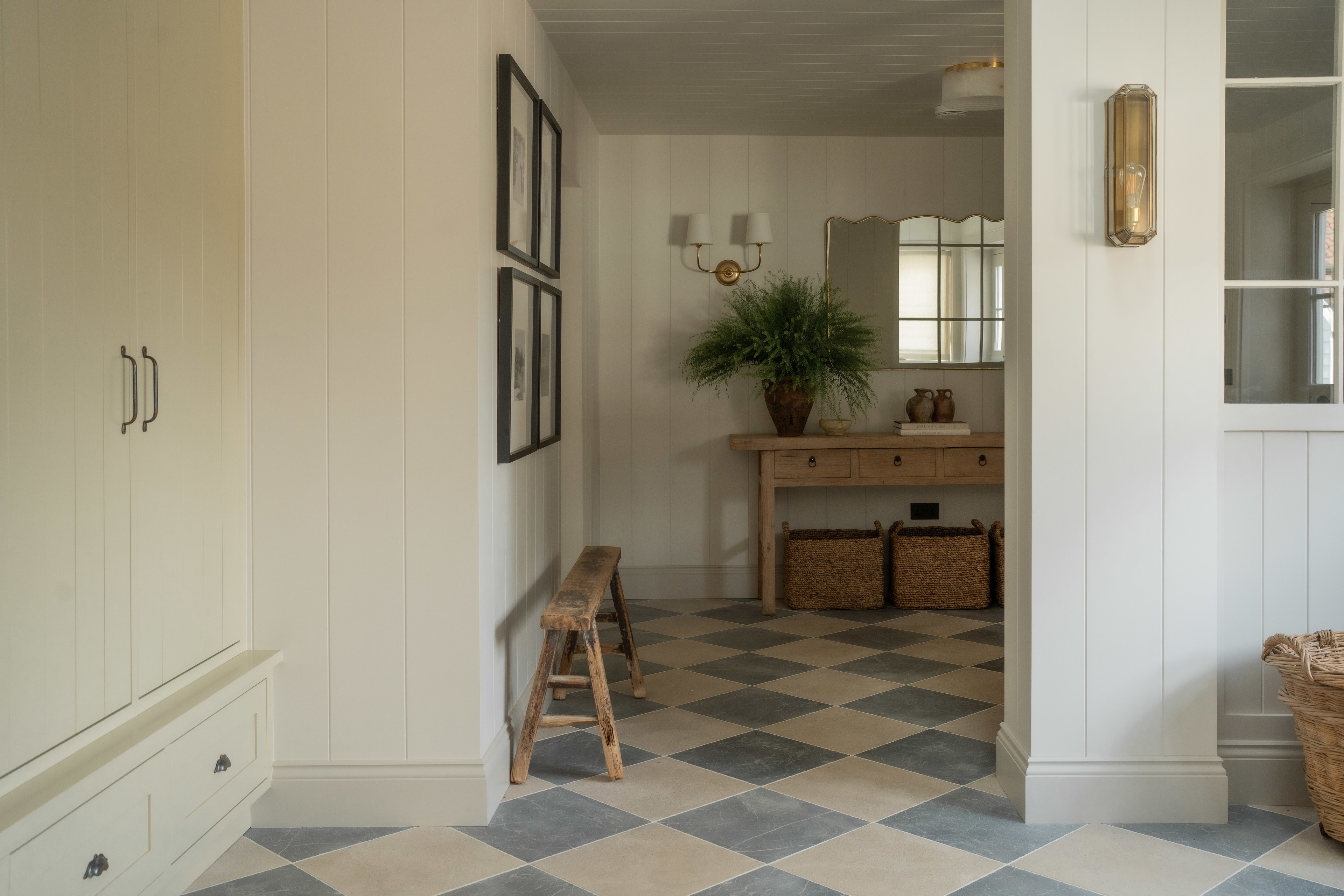 a hallway with a checkered floor and a wooden bench