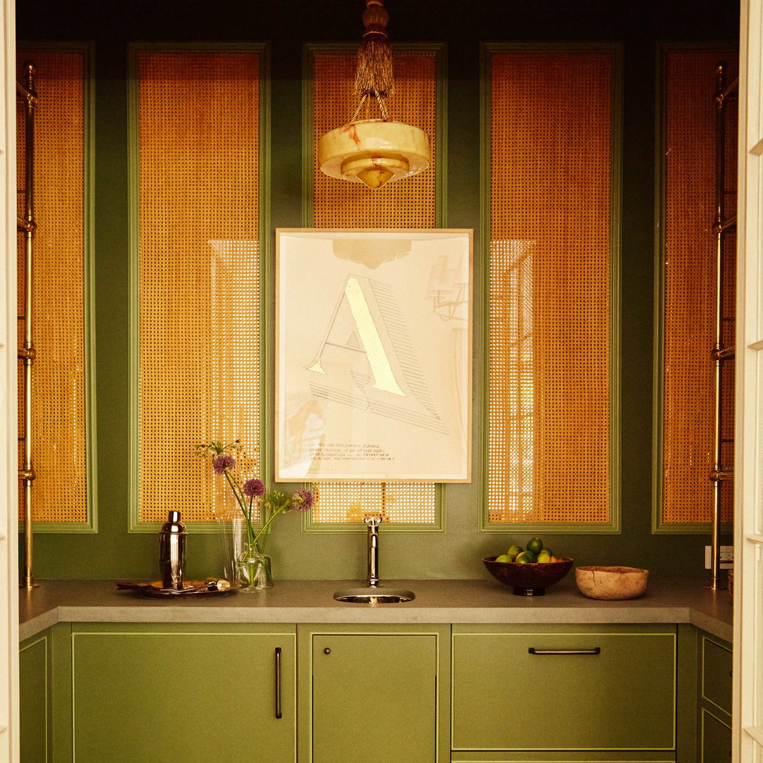 a kitchen with green cabinets and a painting on the wall