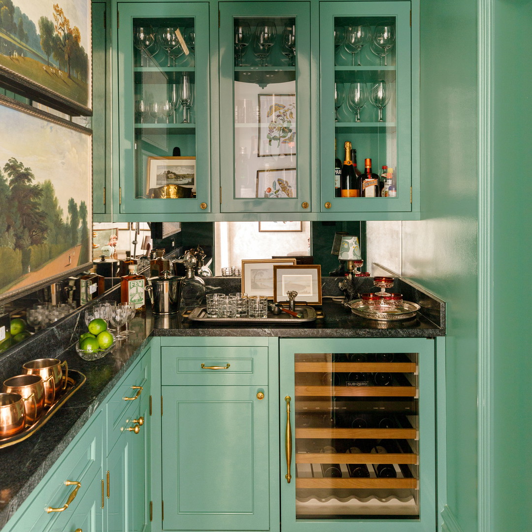 a kitchen with green cabinets and a painting on the wall