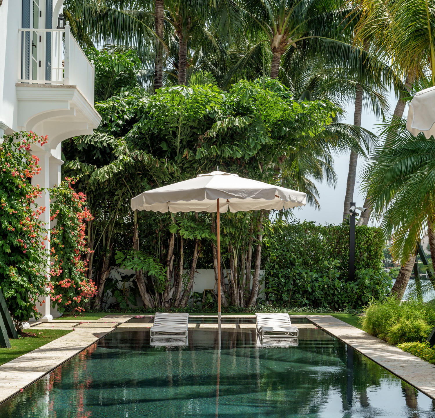 a pool with a white umbrella next to a house