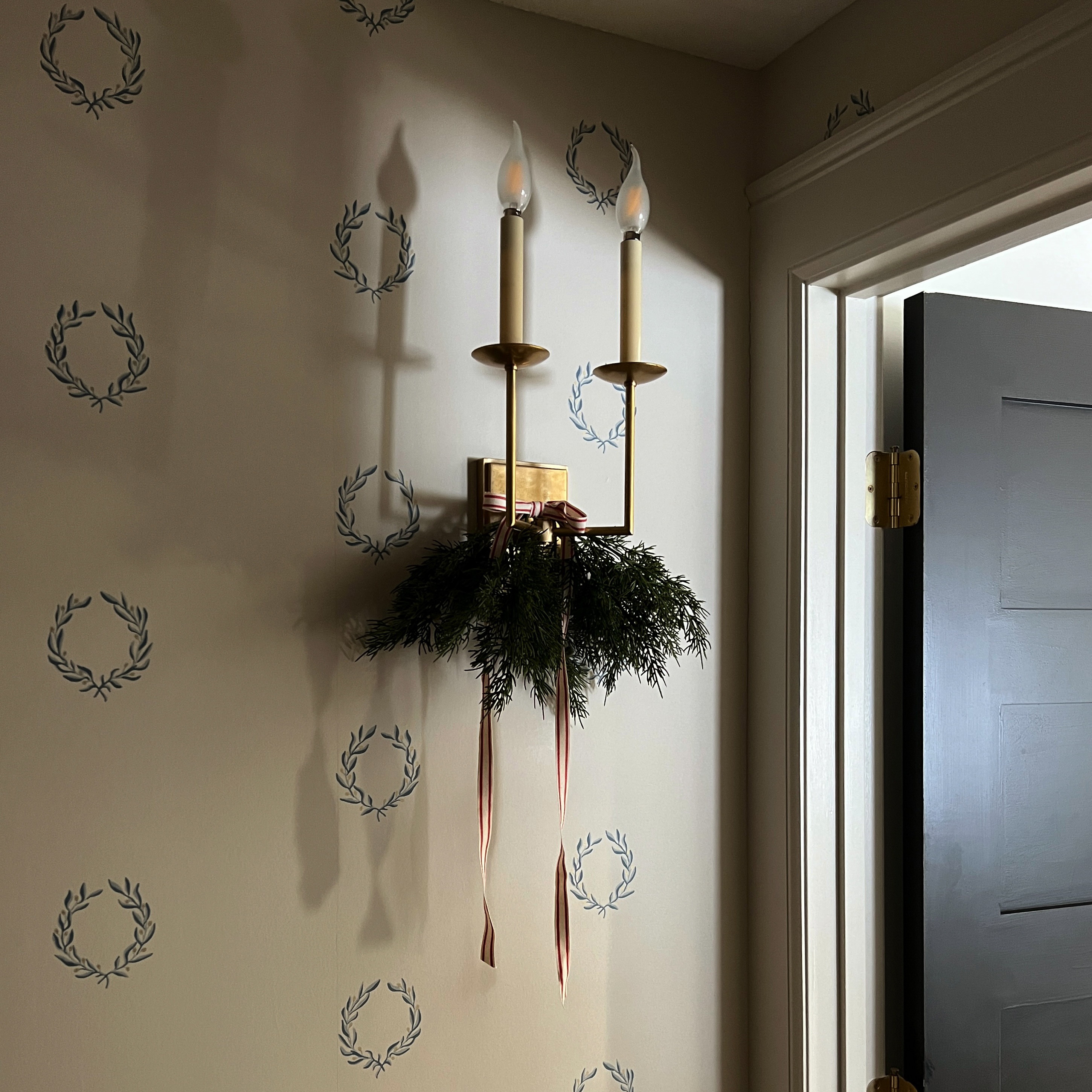 a wall with a candle and a wreath on it