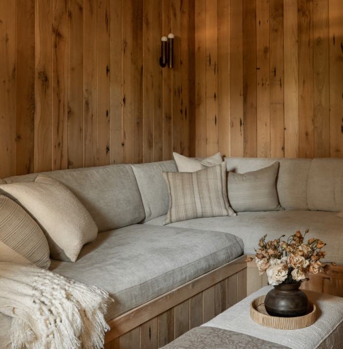 a couch and ottoman in a room with wood paneling