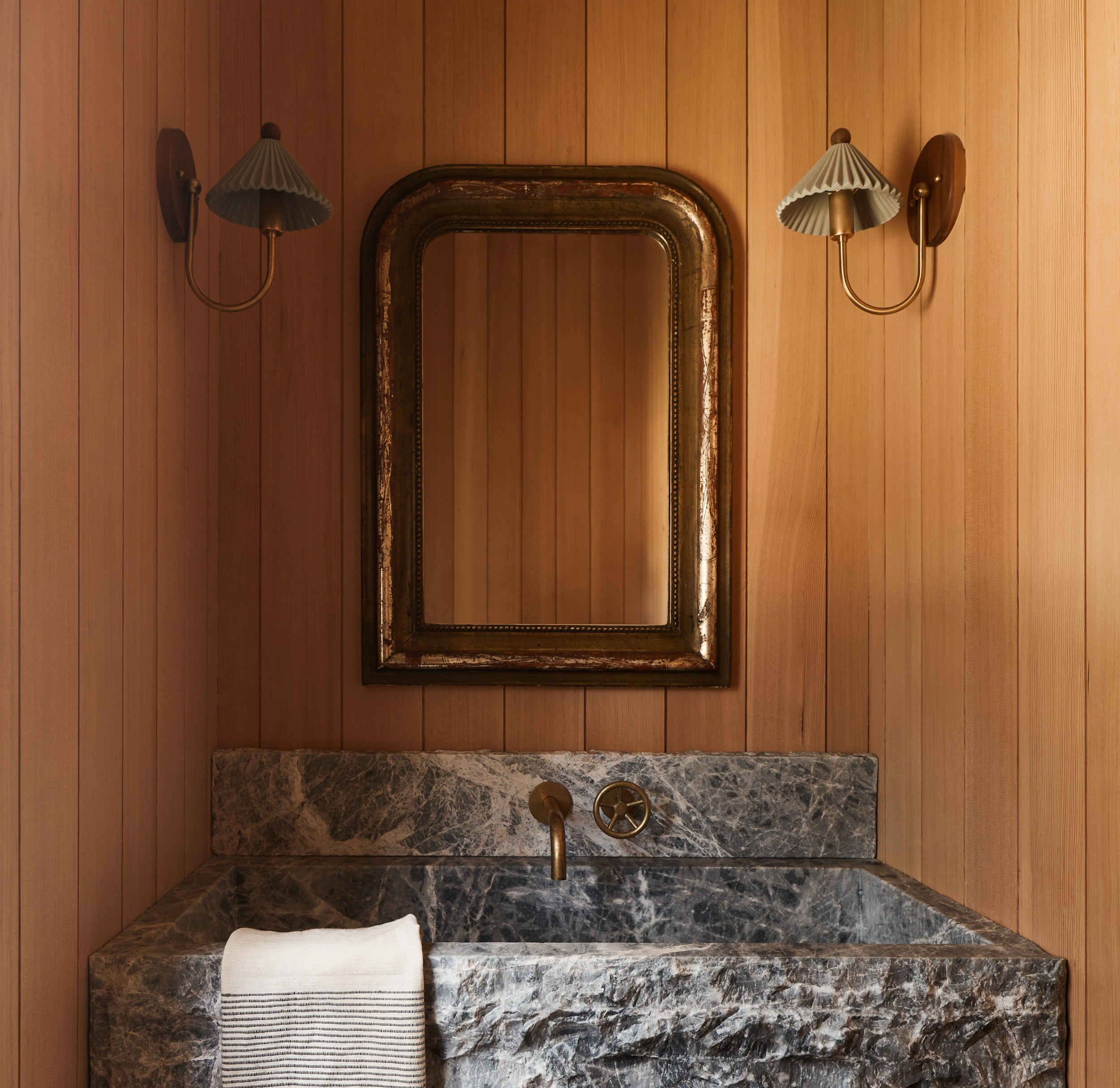 a bathroom with a marble sink and wooden walls