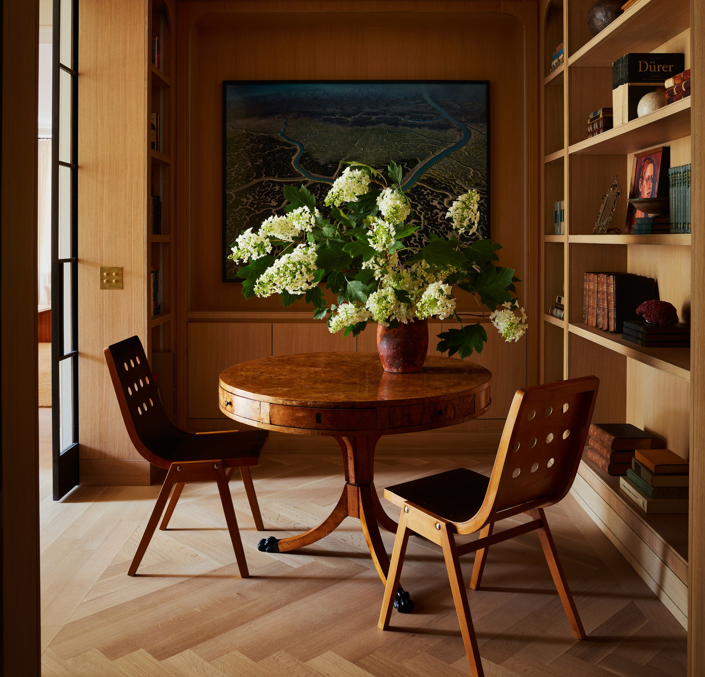 a room with a table and chairs and a painting on the wall