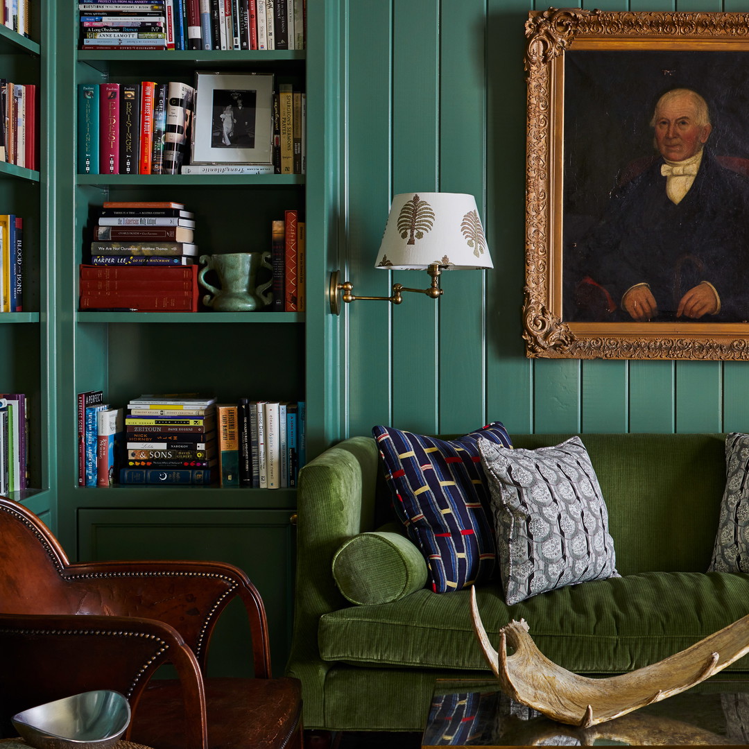 a living room with green walls and a painting on the wall