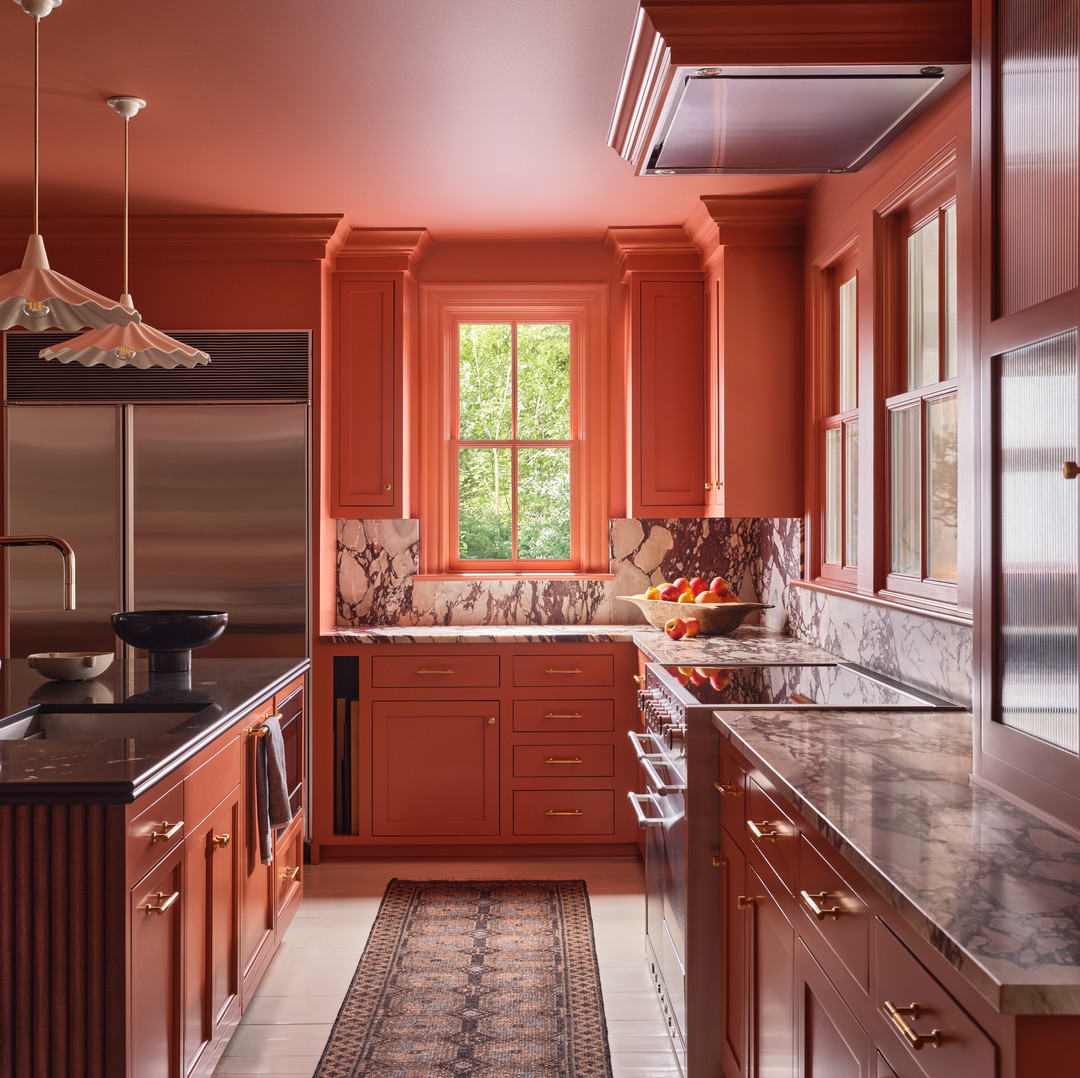 a kitchen with orange walls and marble counter tops