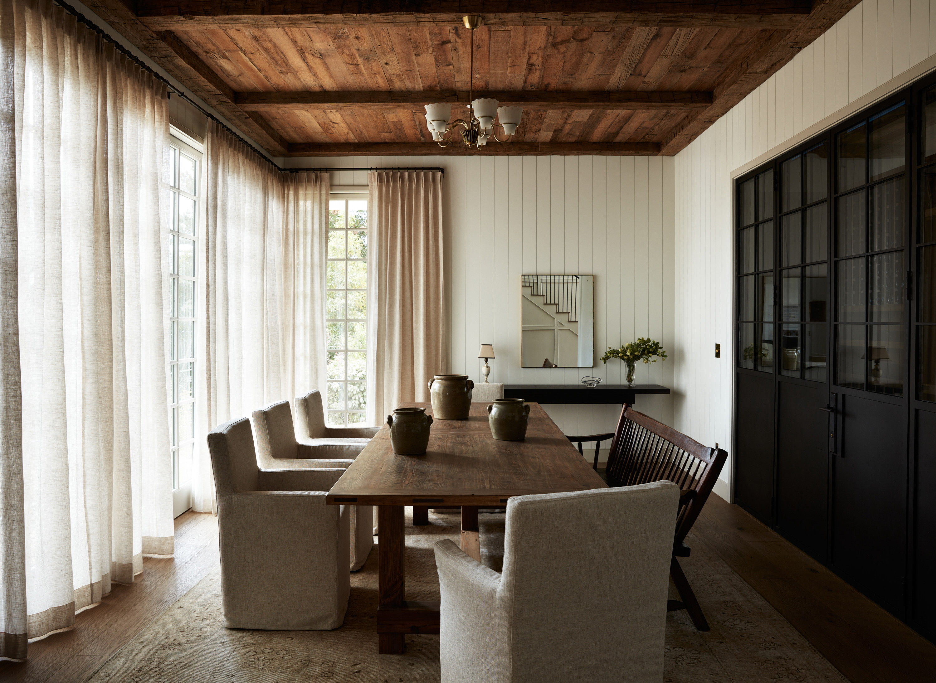 a dining room with a wooden table surrounded by white chairs