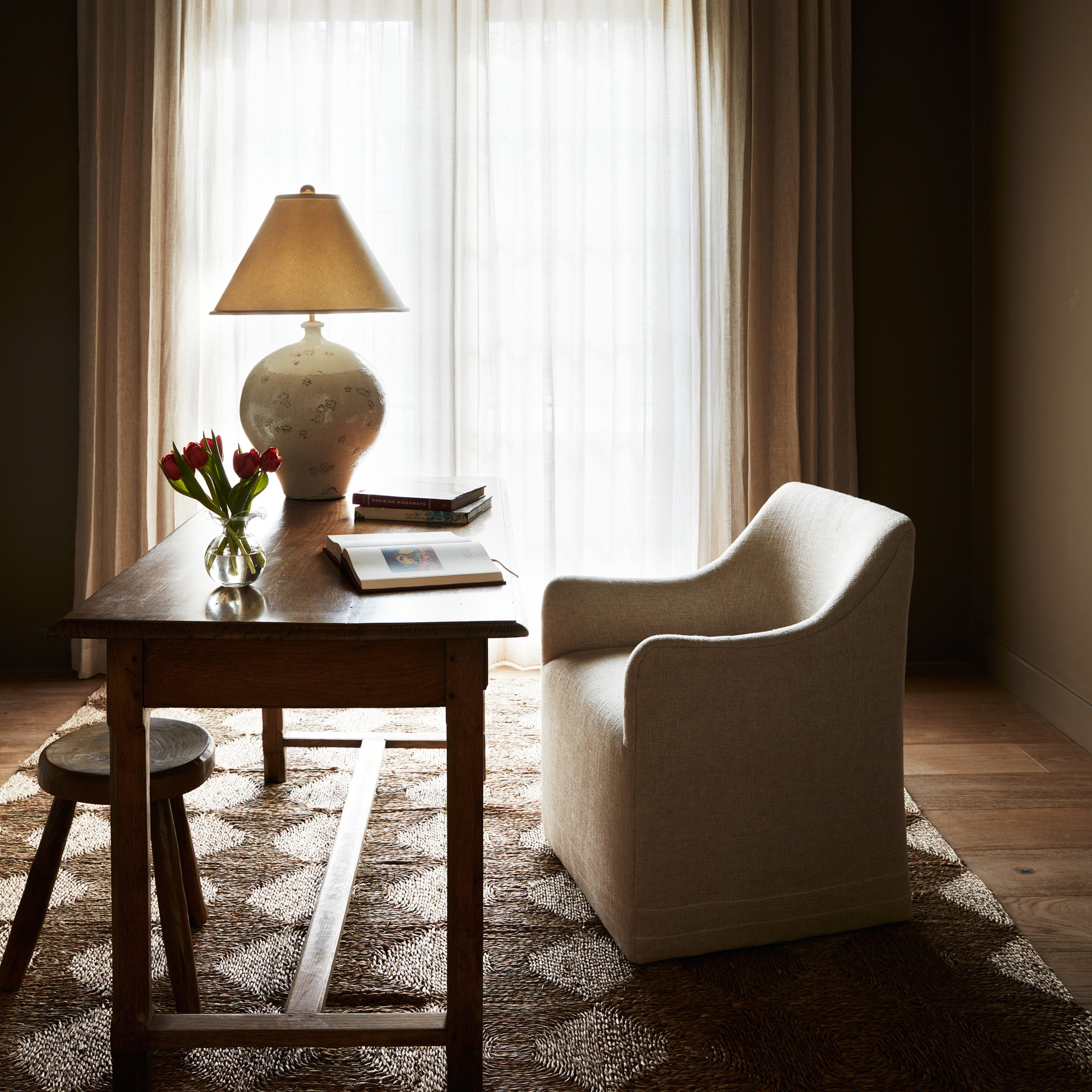 a living room with a table, chair and lamp