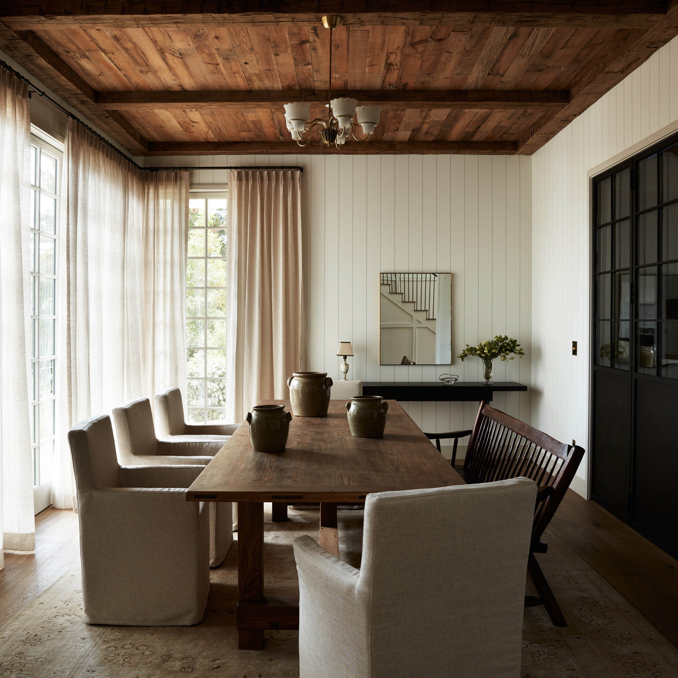 a dining room with a wooden table surrounded by white chairs