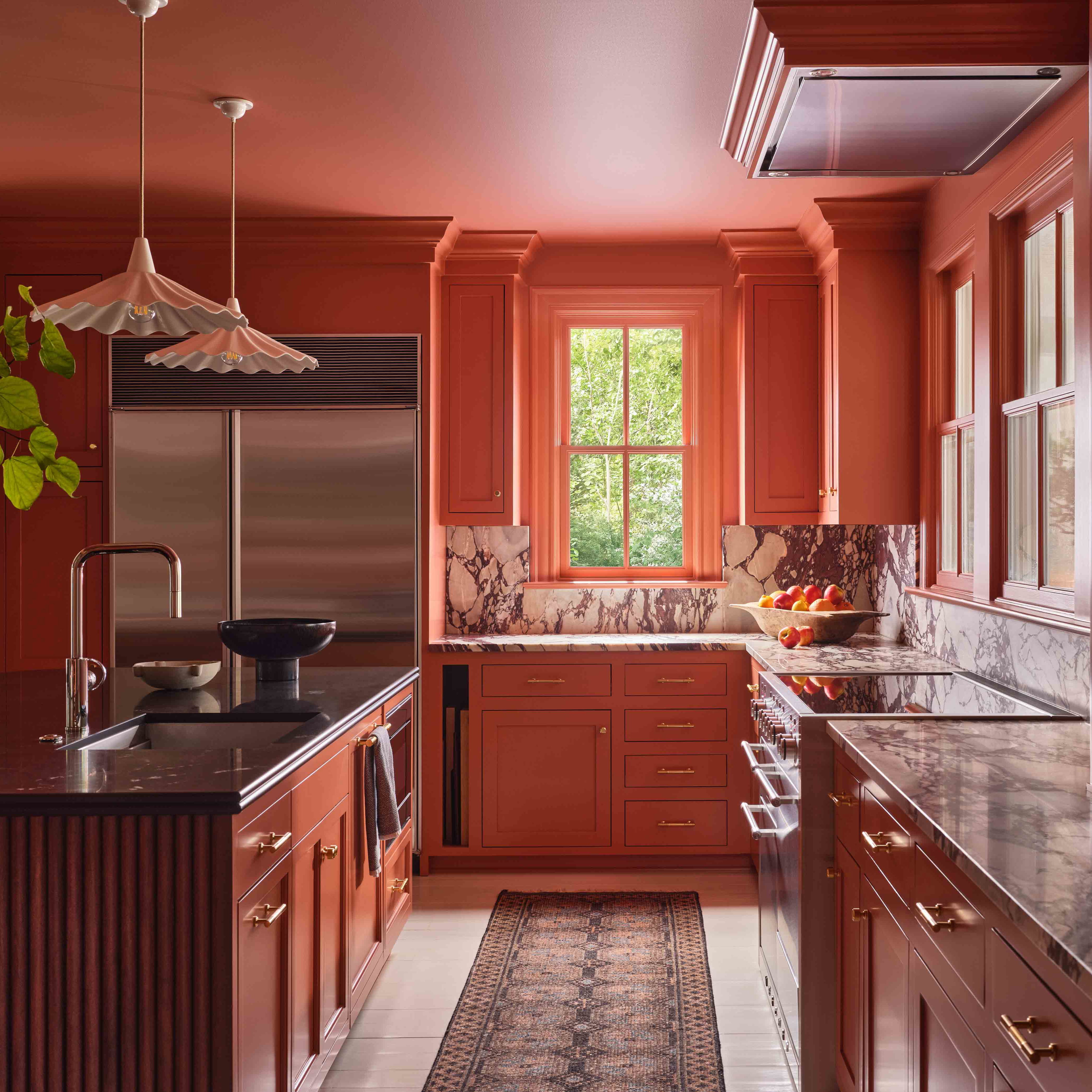 a kitchen with red cabinets and marble counter tops