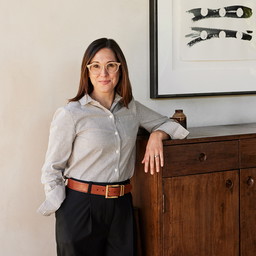 a woman standing next to a wooden cabinet