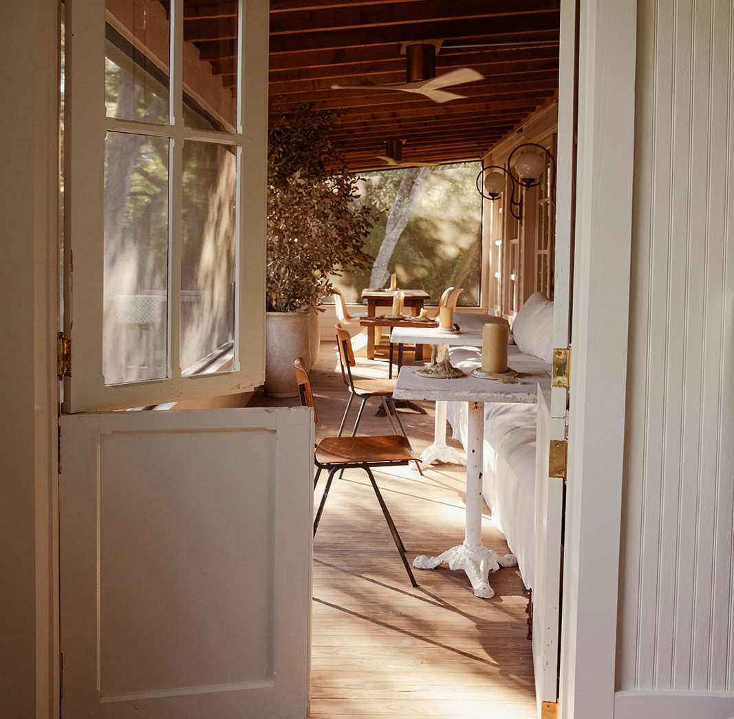 an open door leading to a porch with a table and chairs