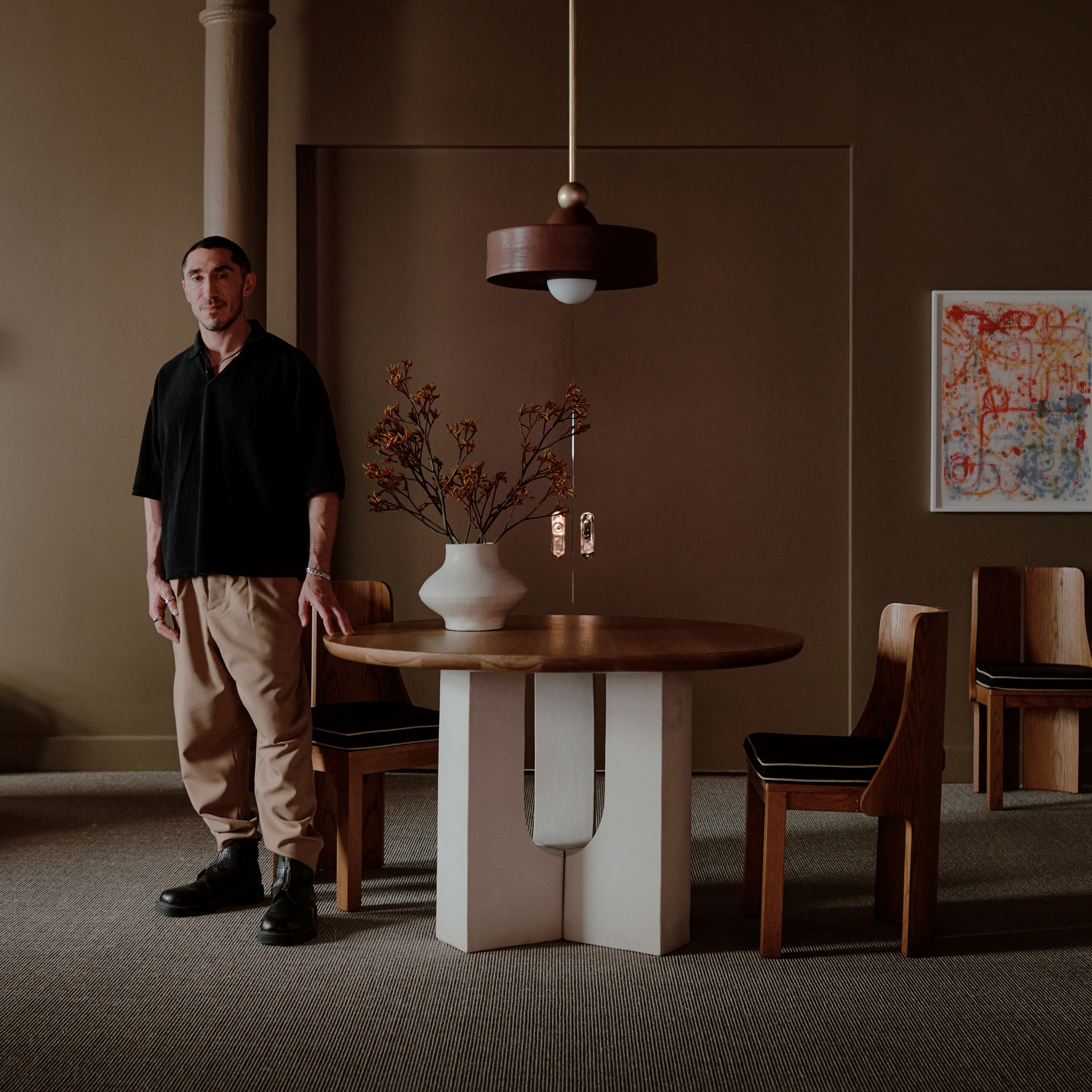 a man standing next to a table with a vase on it