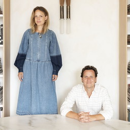 a man and a woman sitting at a table in front of a clock