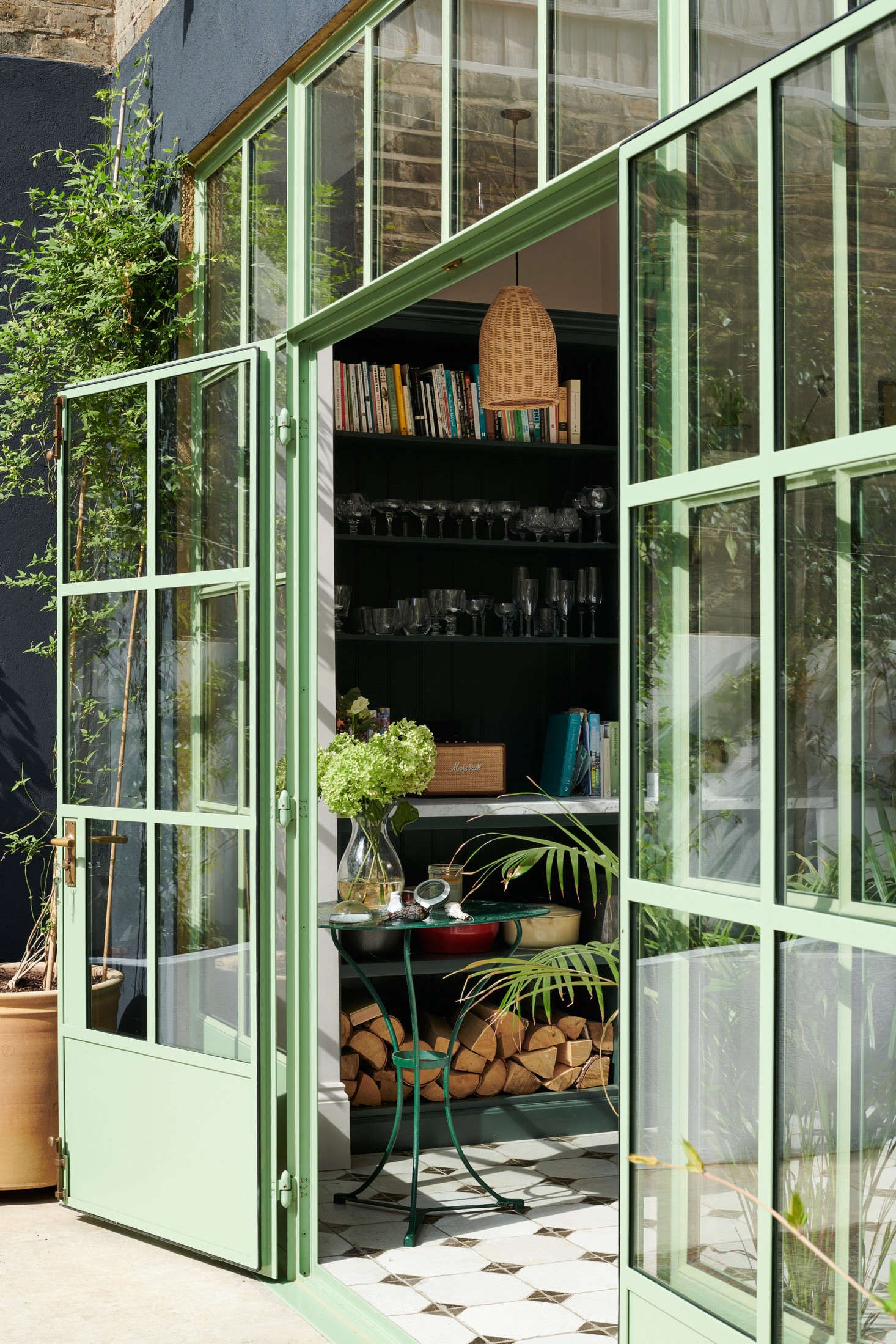 a room with green glass doors and a table with a potted plant in it