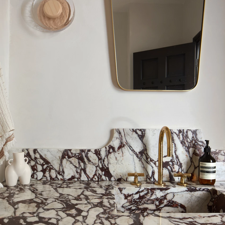 a bathroom with a marble counter top and a gold faucet