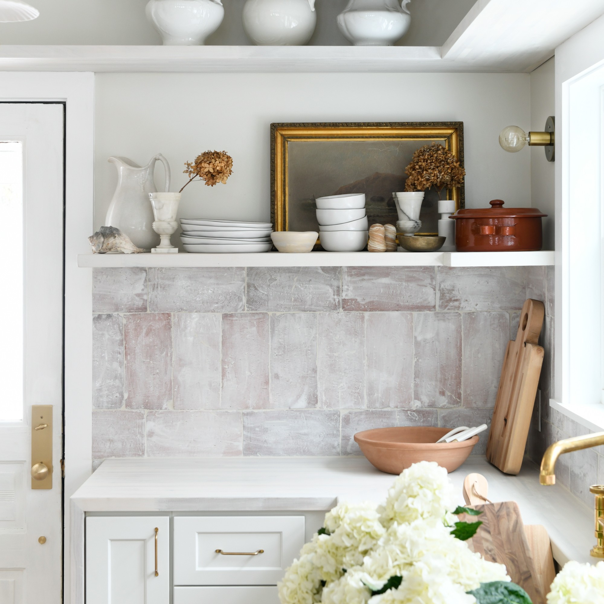 a kitchen with white cabinets and white flowers