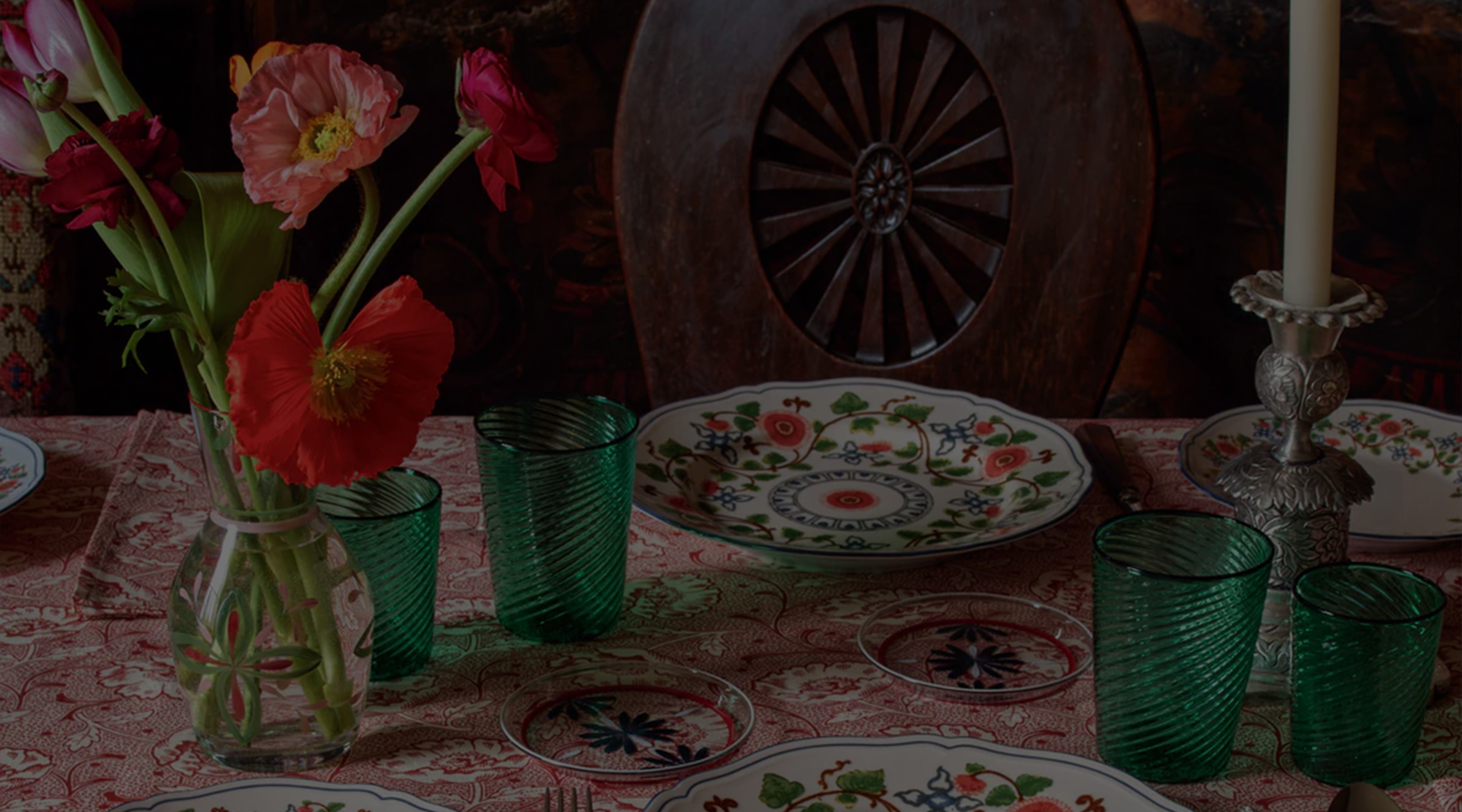 a table topped with plates and vases filled with flowers