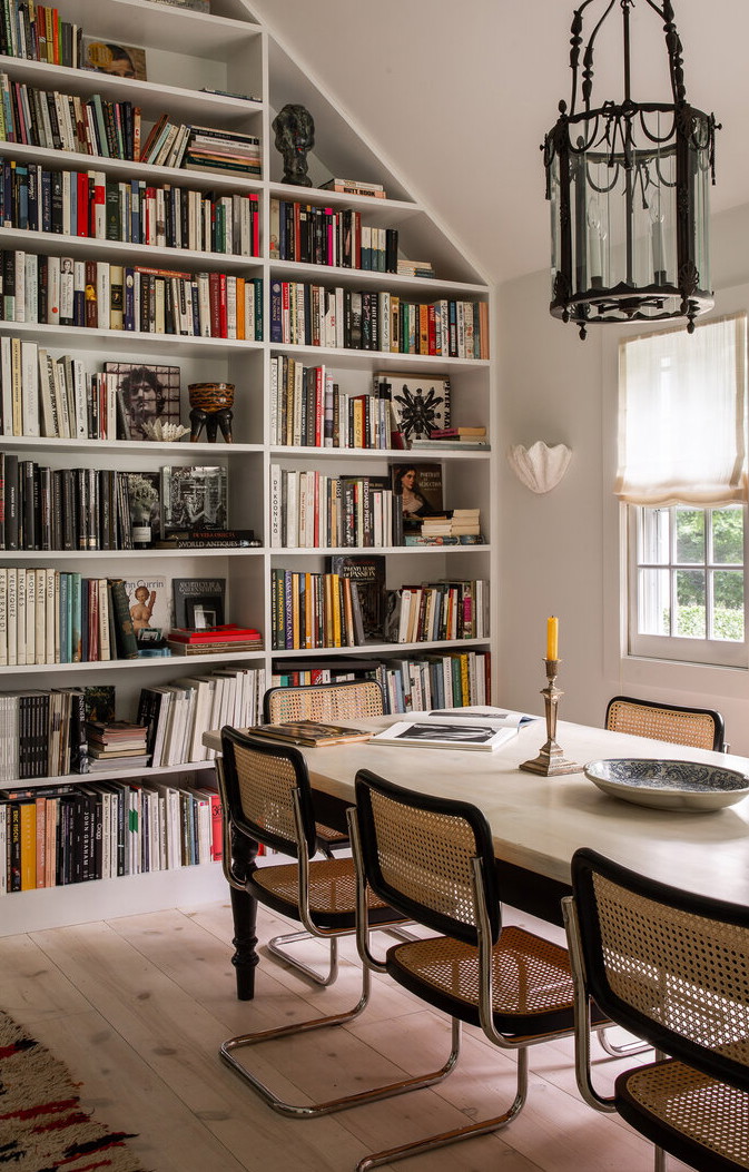 a dining room table with chairs and a bookshelf