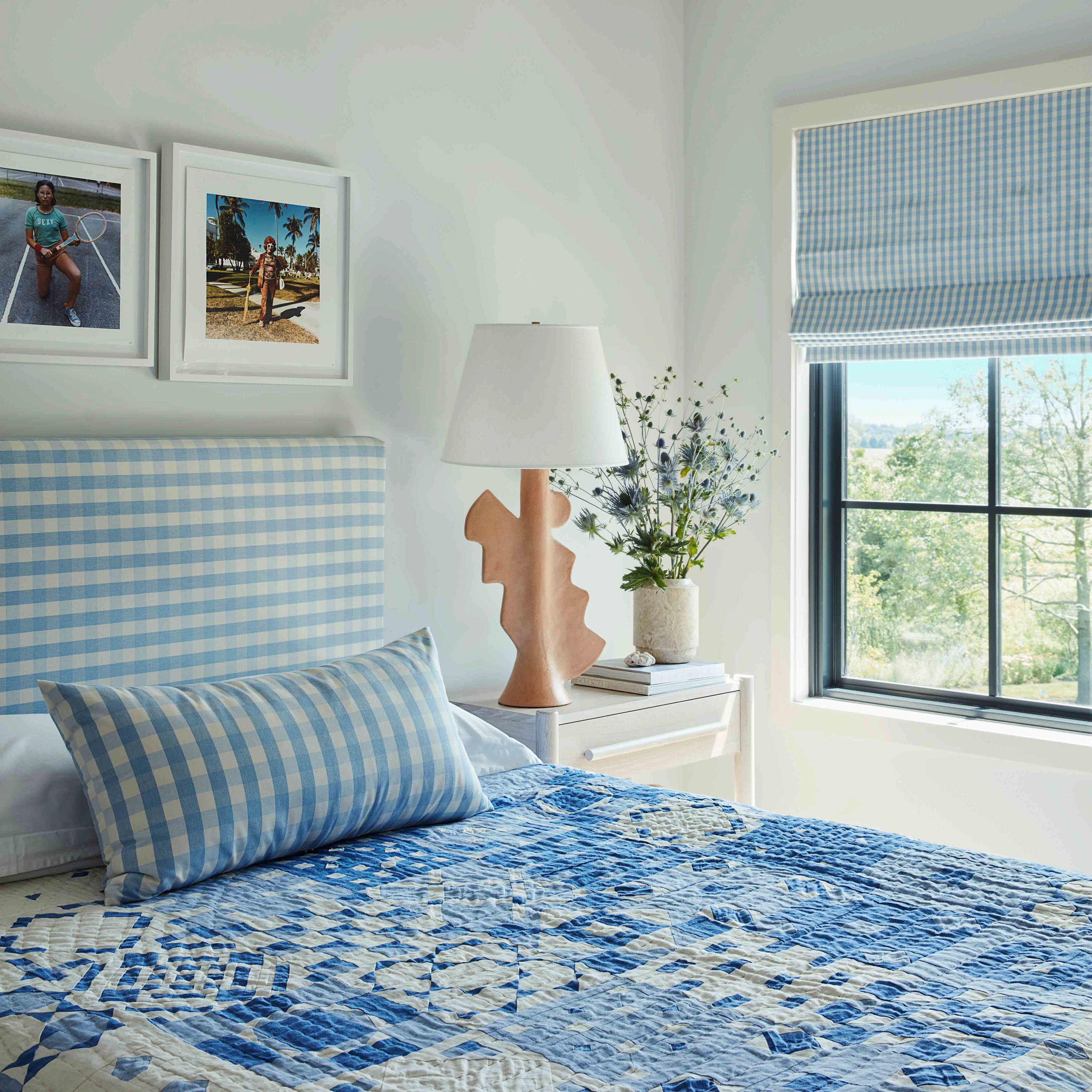 a bed with a blue and white bedspread next to a window