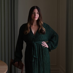 a woman in a green robe standing in a dark room