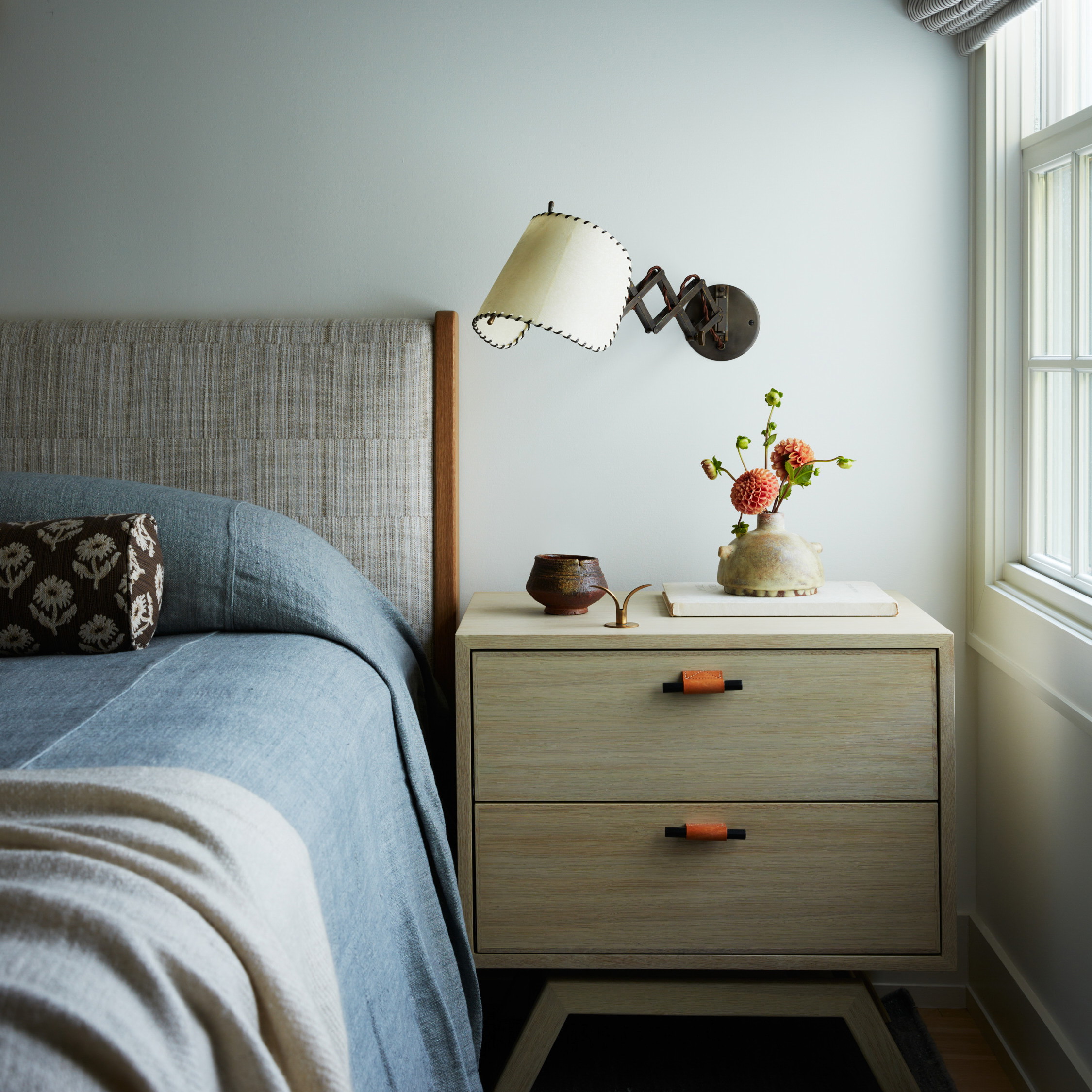 a bedroom with a bed and a nightstand with a lamp on top of it
