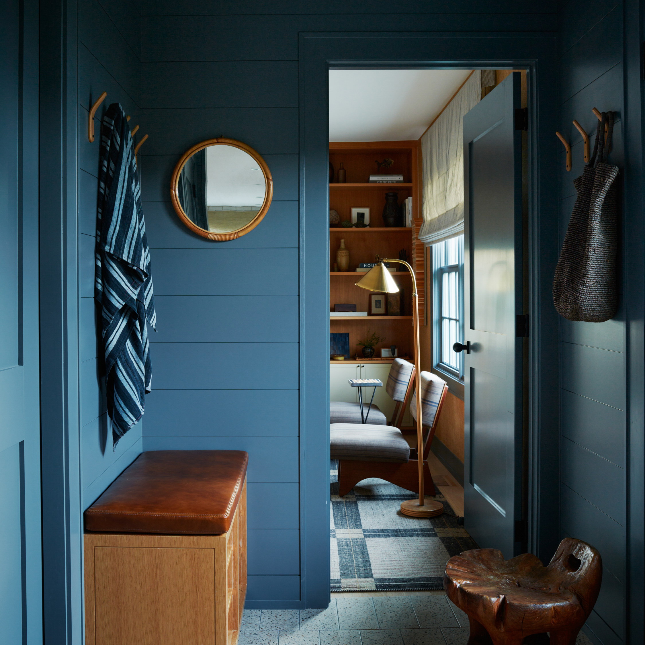 a blue hallway with a bench and mirror
