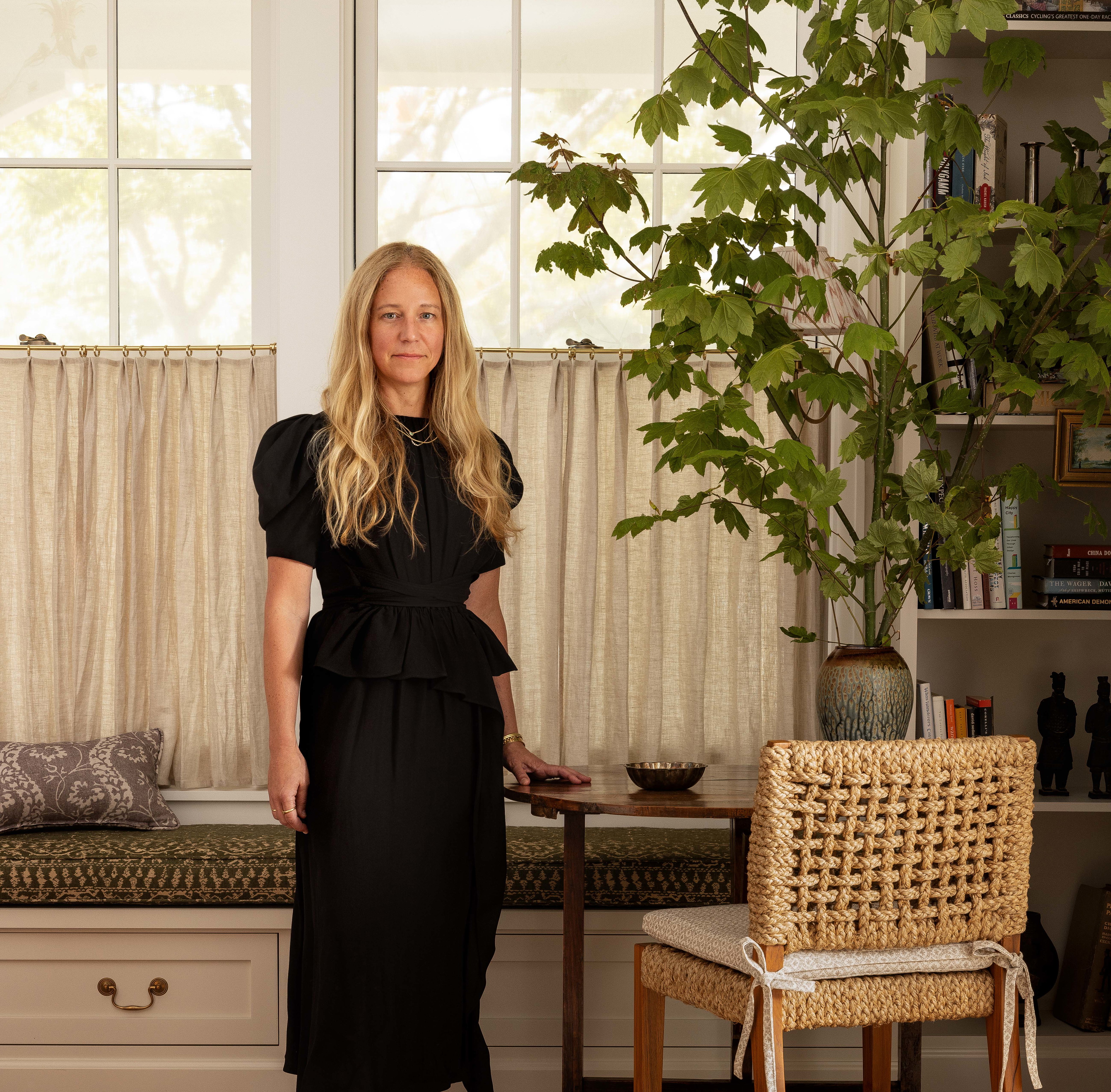 a woman in a black dress standing in front of a window