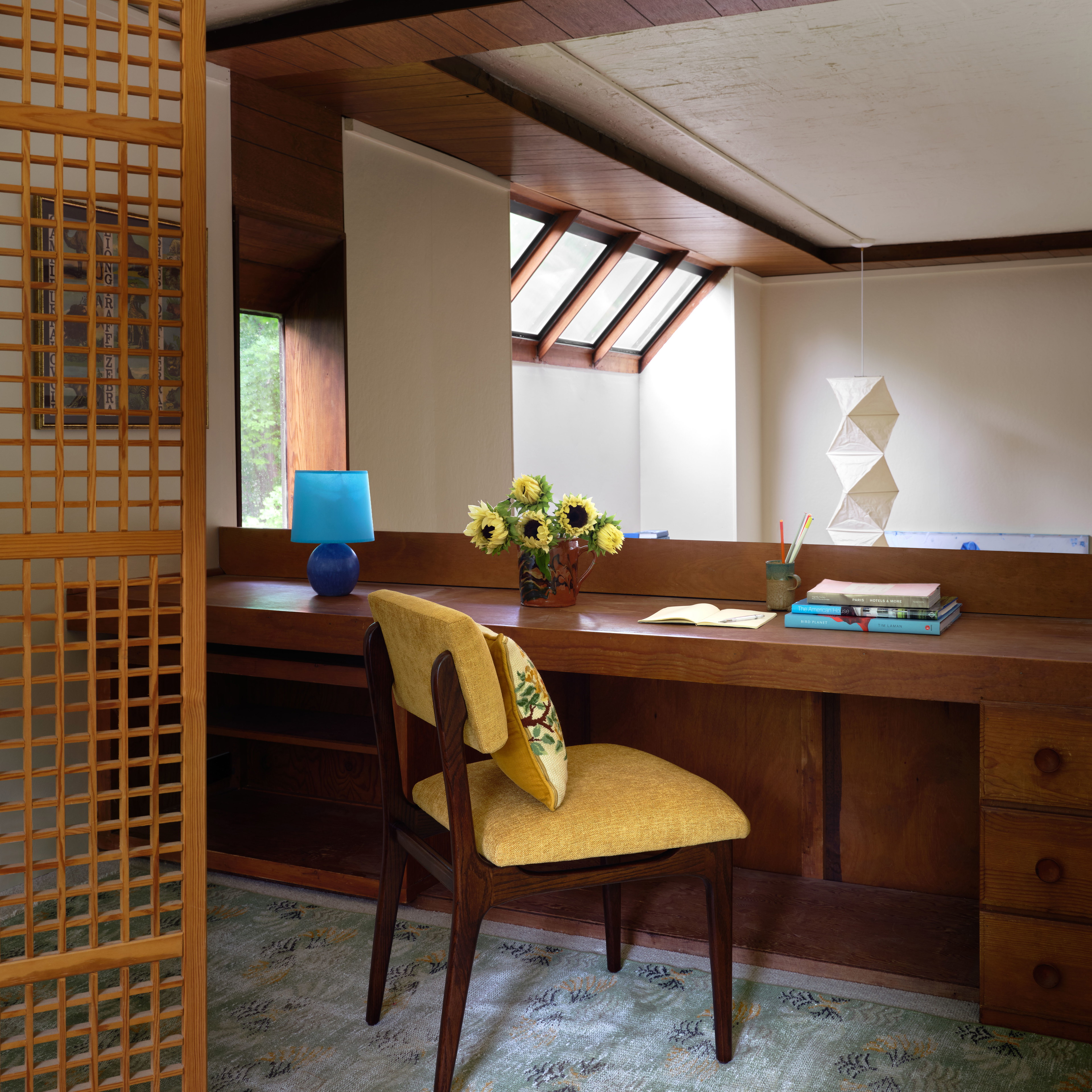 a desk with a chair and a vase of flowers