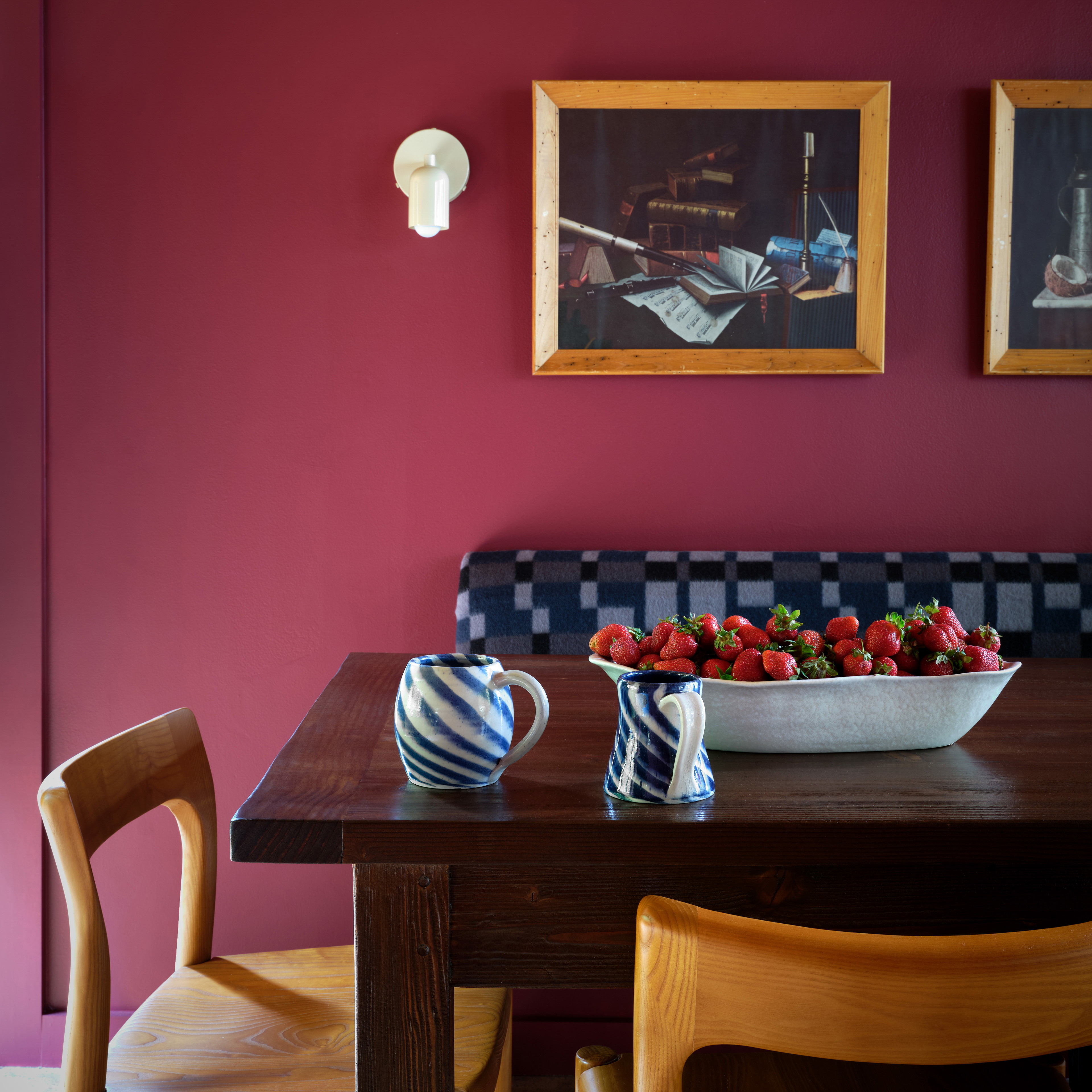 a bowl of strawberries sits on a table in a dining room
