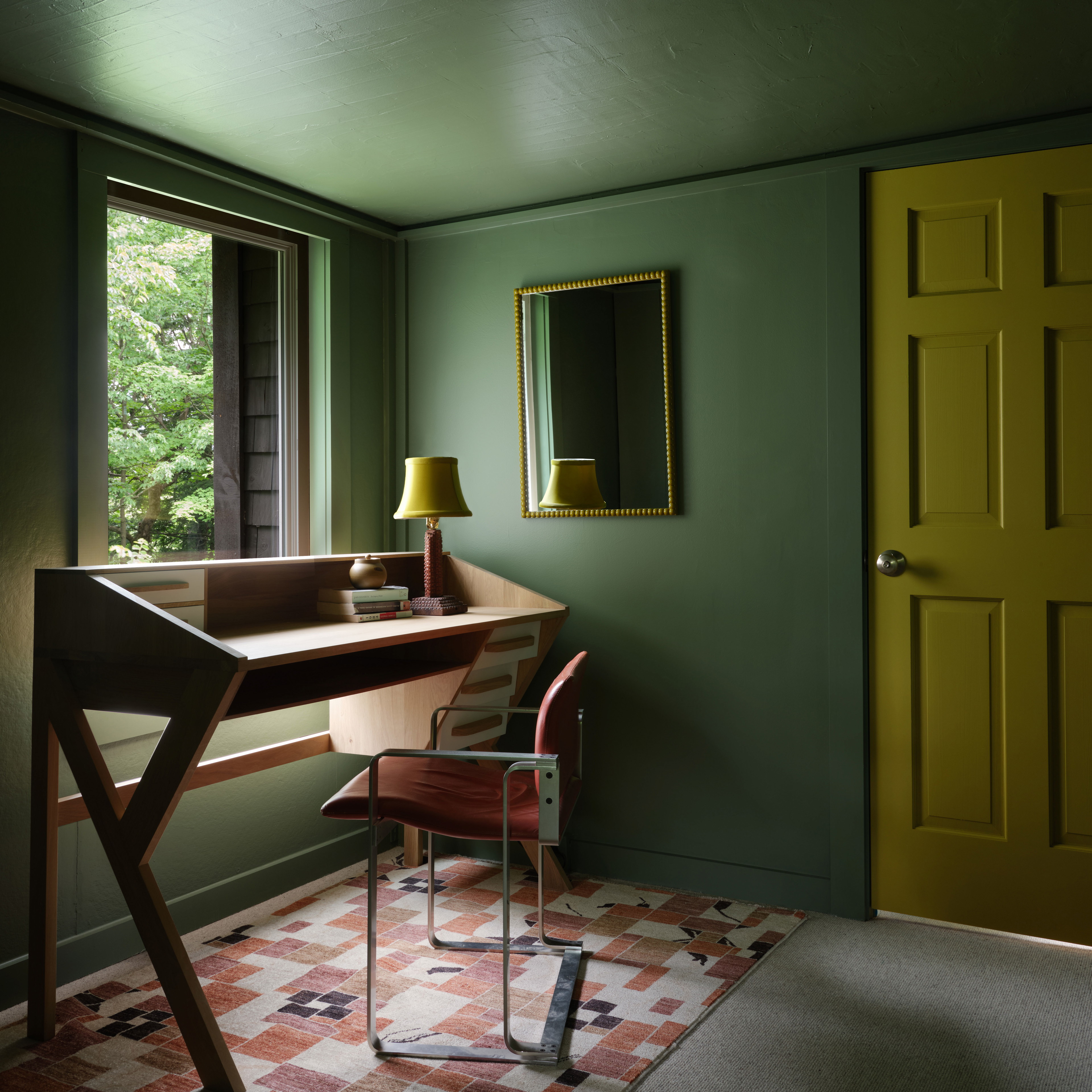 a room with a desk, chair, and a yellow door