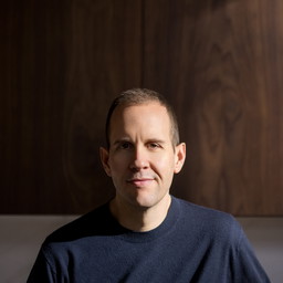 a man standing in front of a wooden wall