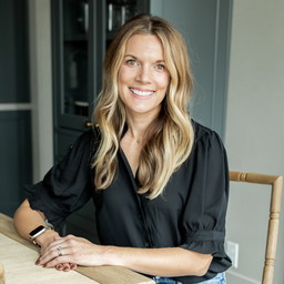 a woman sitting at a table smiling for the camera