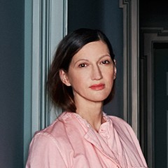 a woman standing in front of a door wearing a pink shirt