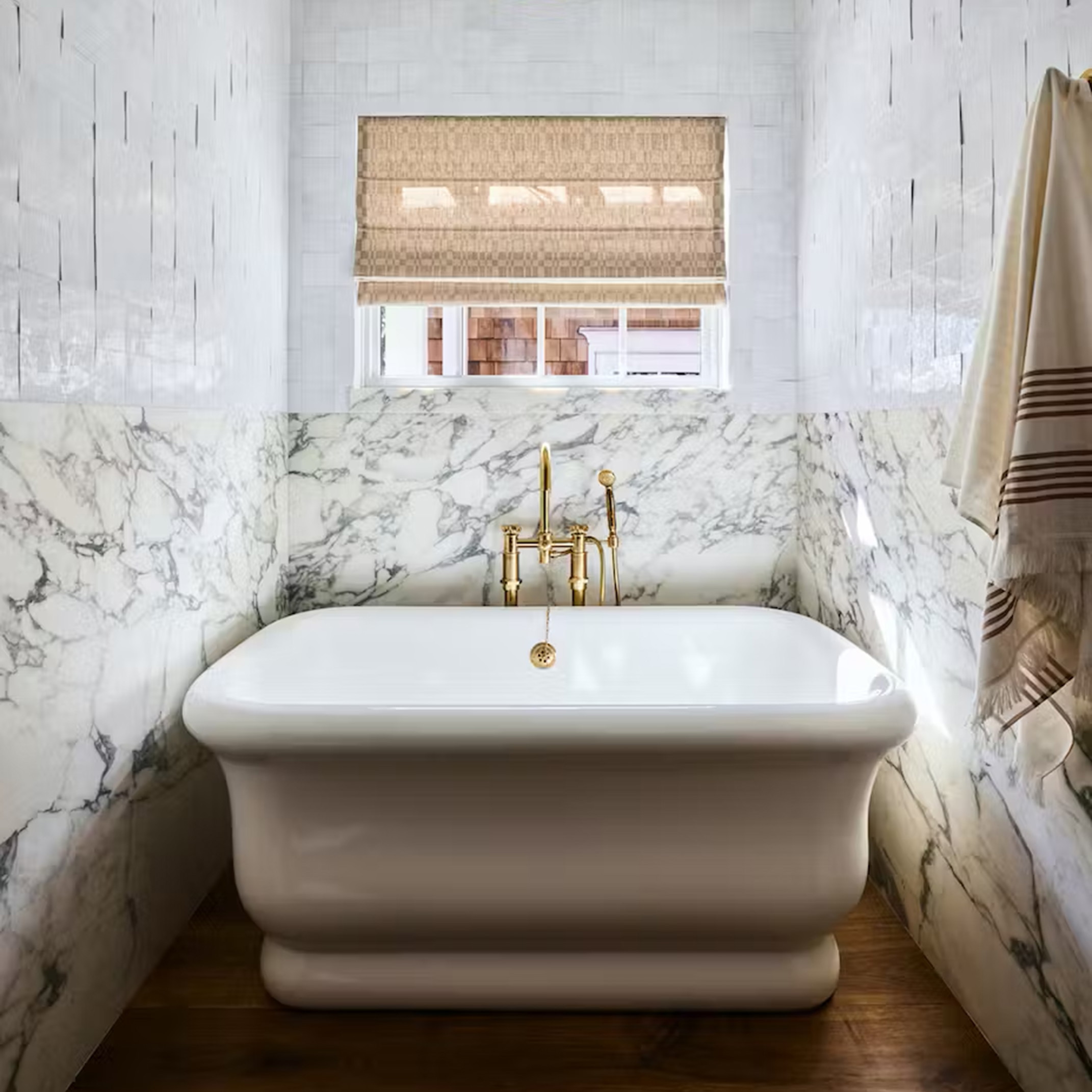 a white bath tub sitting under a window in a bathroom
