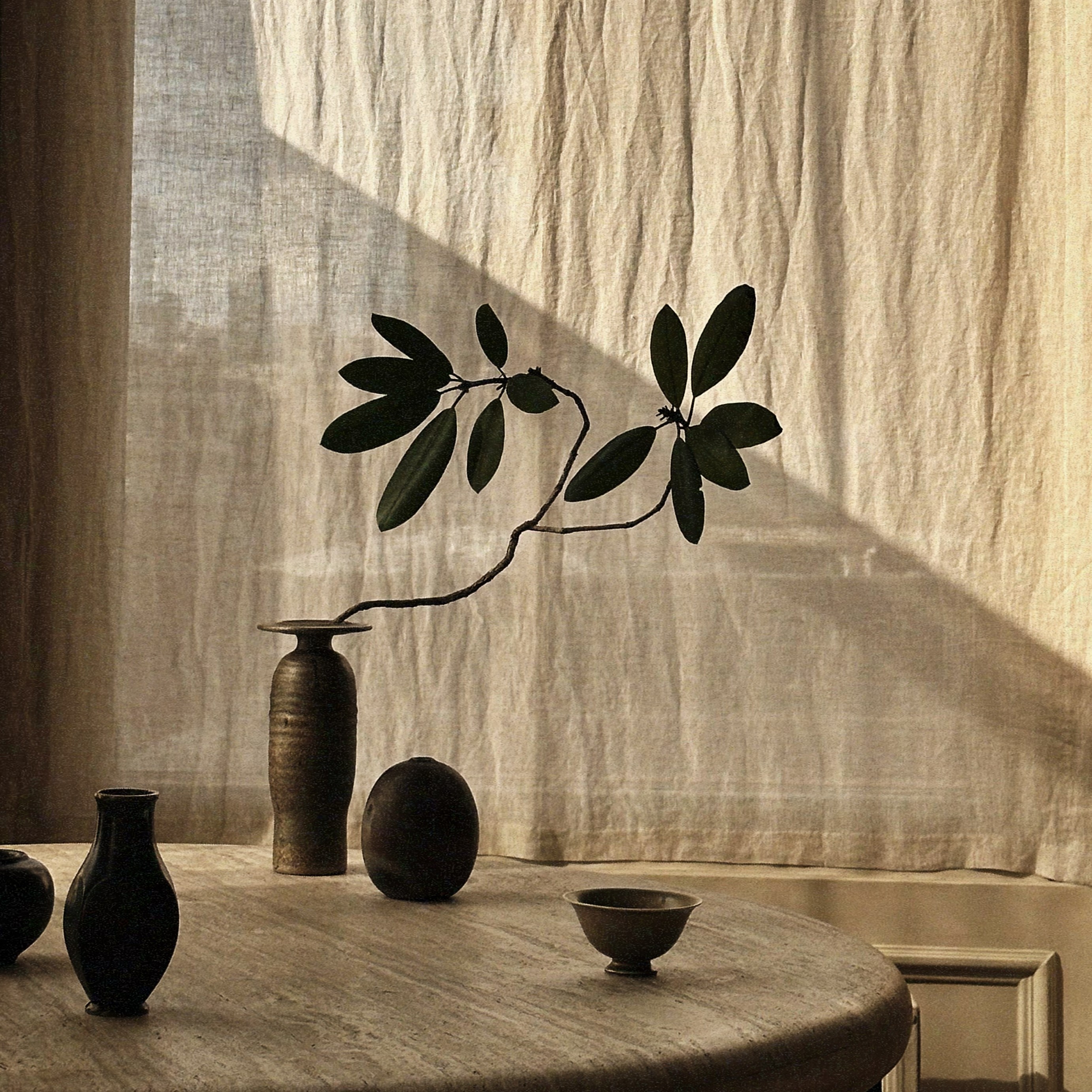 a table with vases and a vase on it in front of a window
