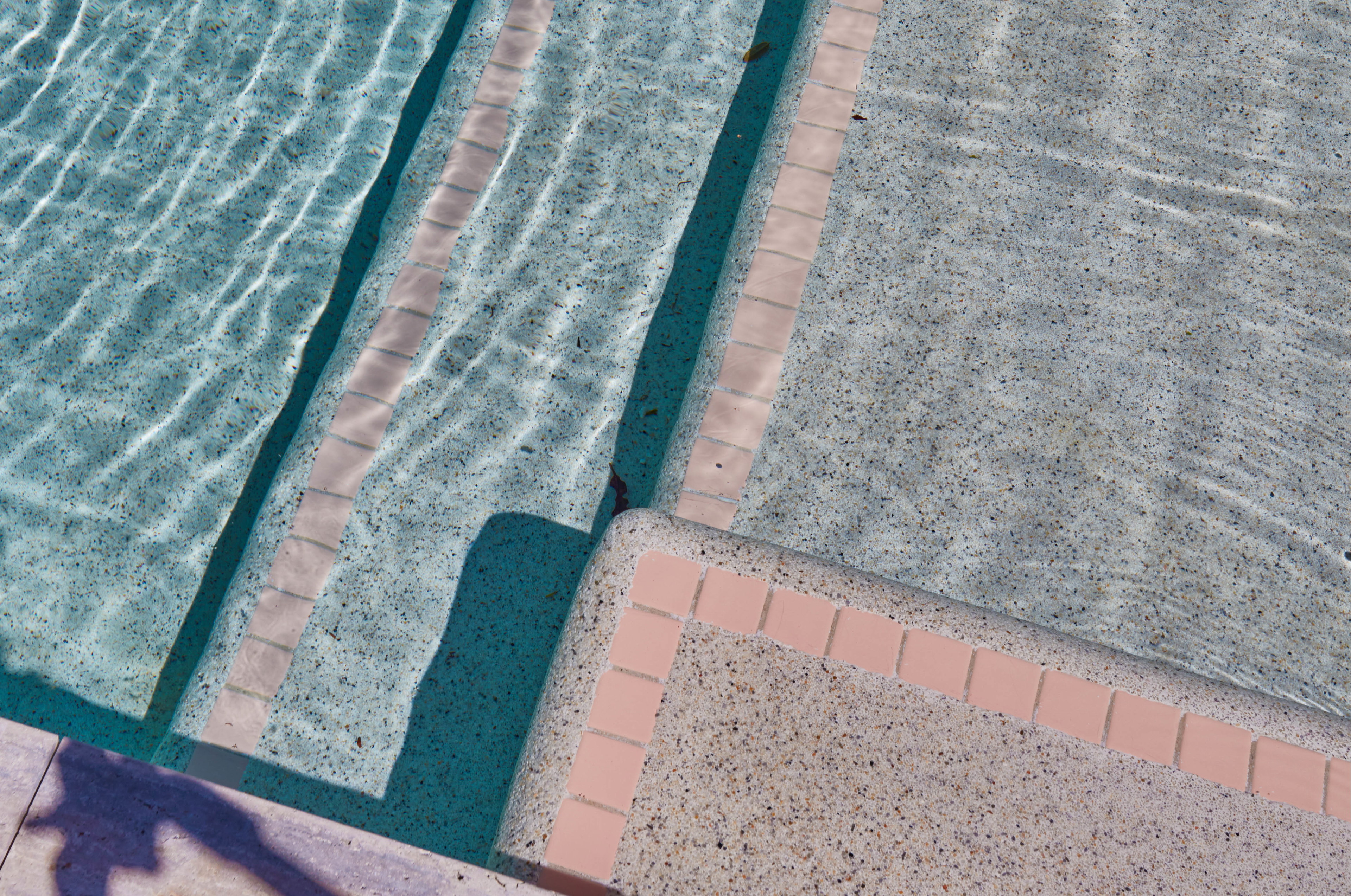 a shadow of a person standing next to a swimming pool
