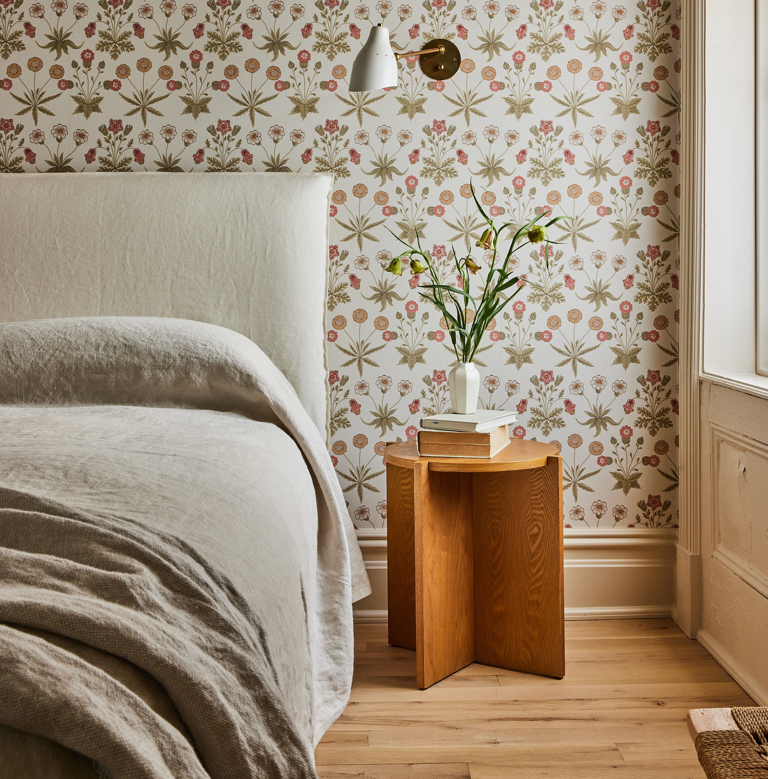 a bedroom with a bed, nightstand, and flower wallpaper