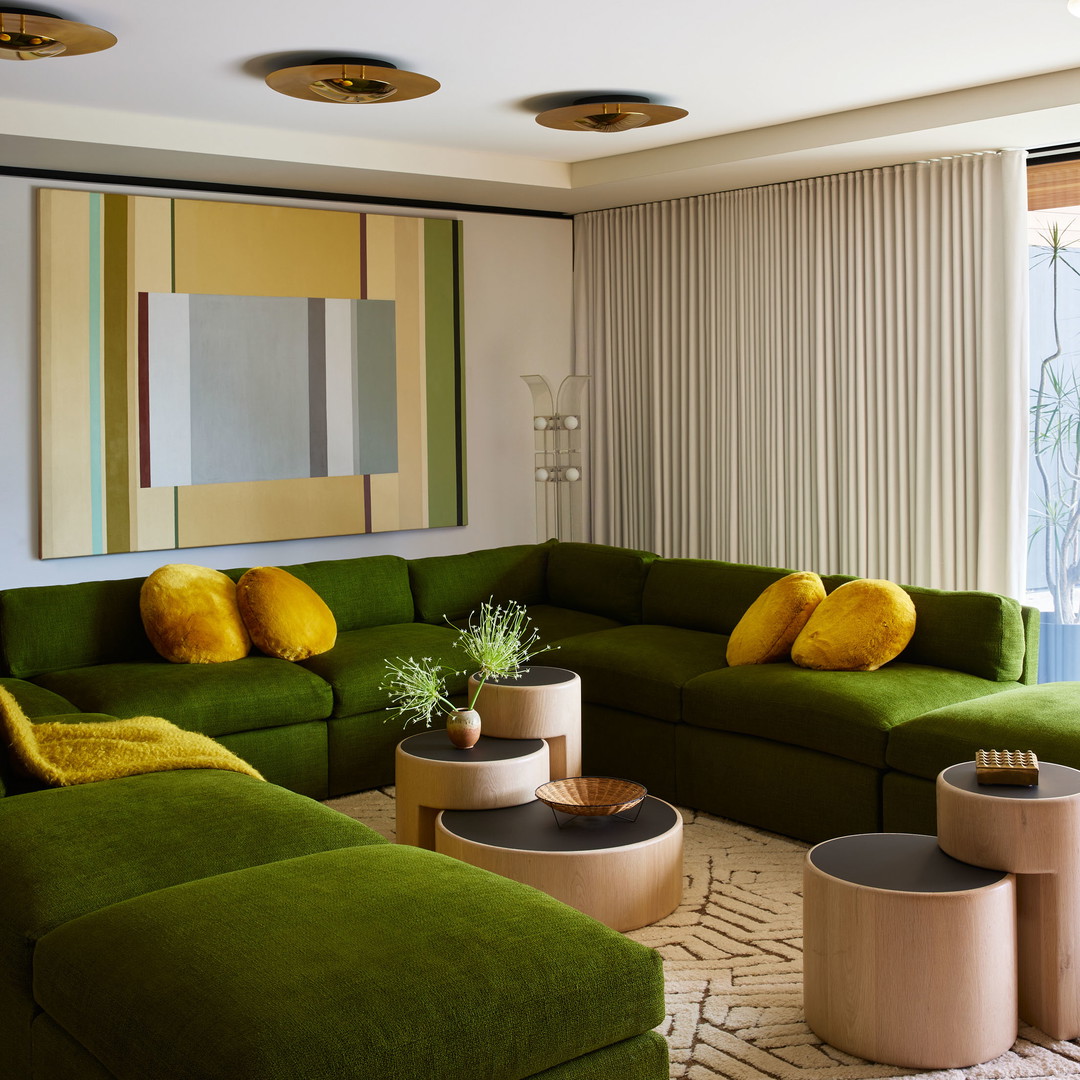 a living room filled with green couches and yellow pillows