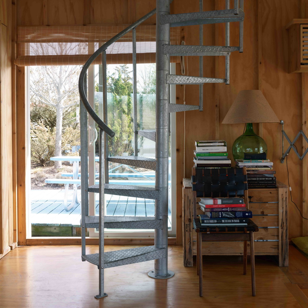 a room with a spiral staircase and a table with a lamp