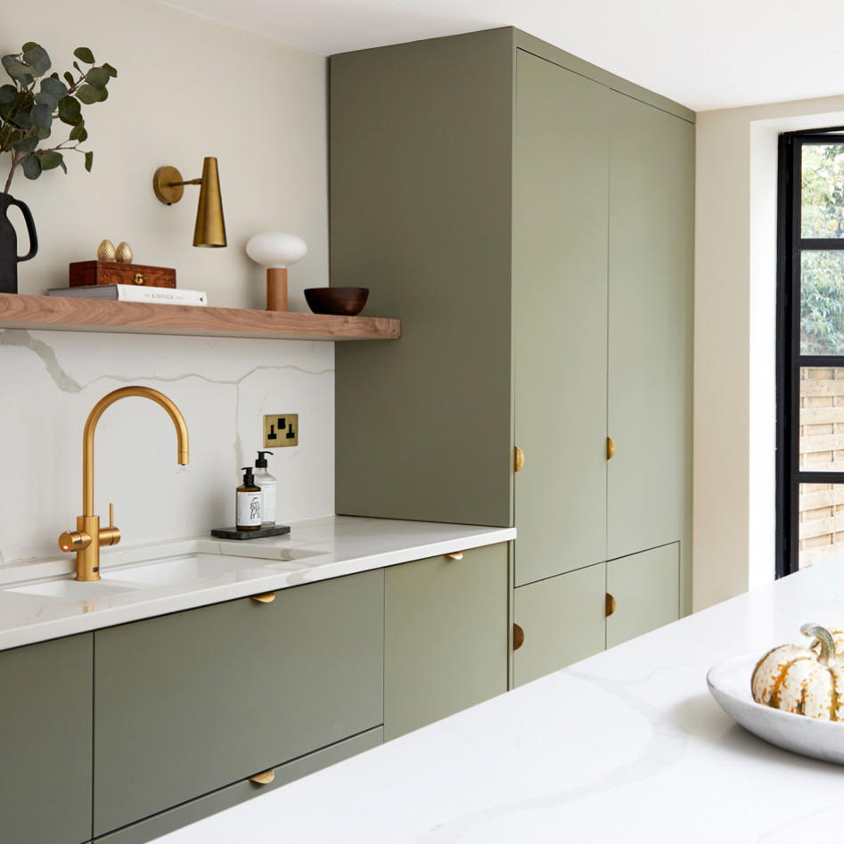 a kitchen with green cabinets and a gold faucet