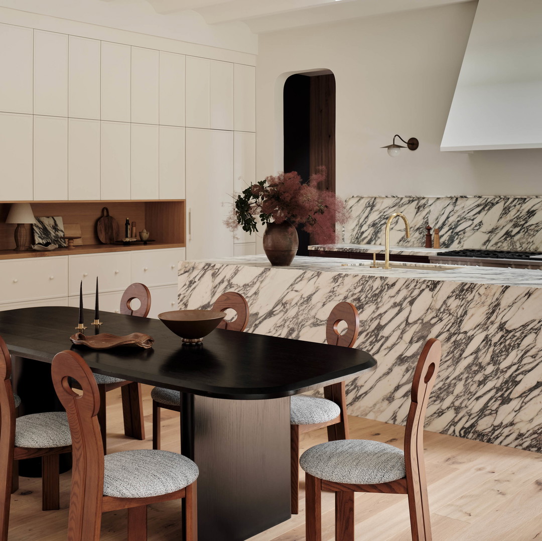 a kitchen with a marble counter top and wooden chairs