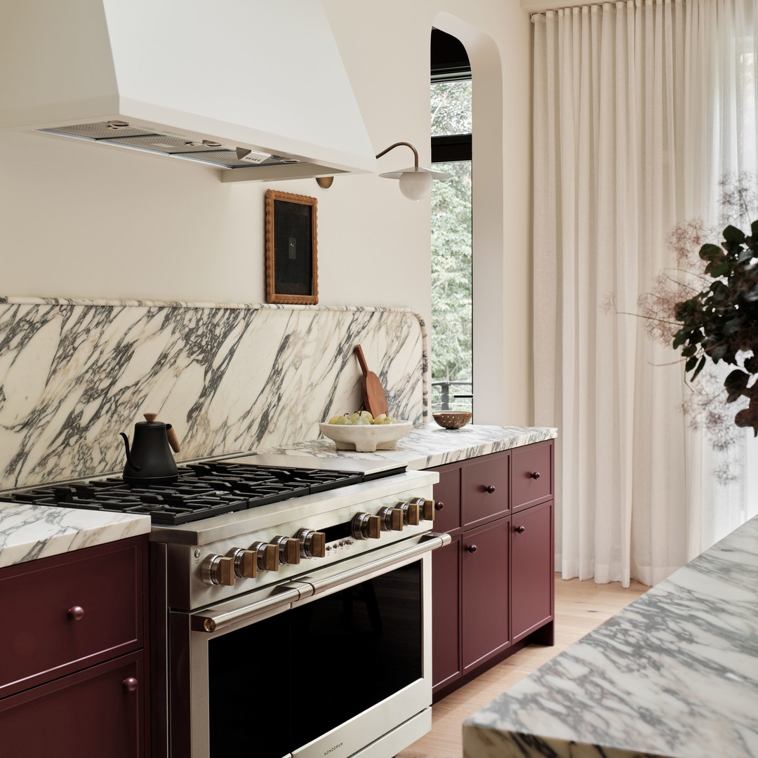 a kitchen with marble counter tops and maroon cabinets