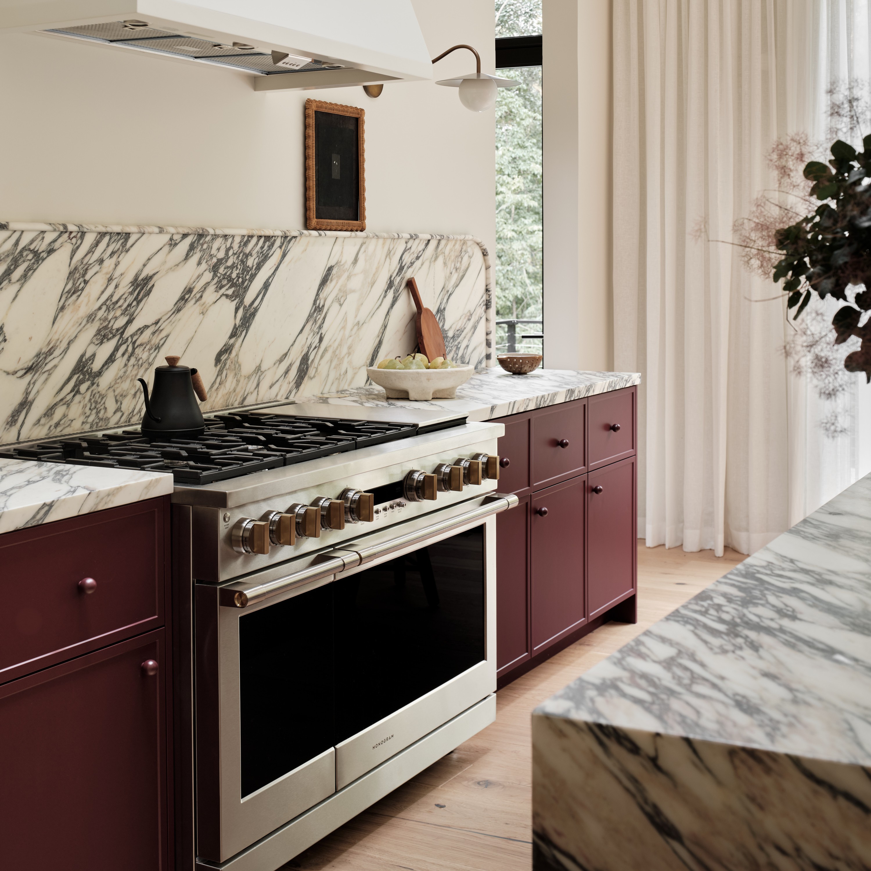 a kitchen with marble counter tops and maroon cabinets