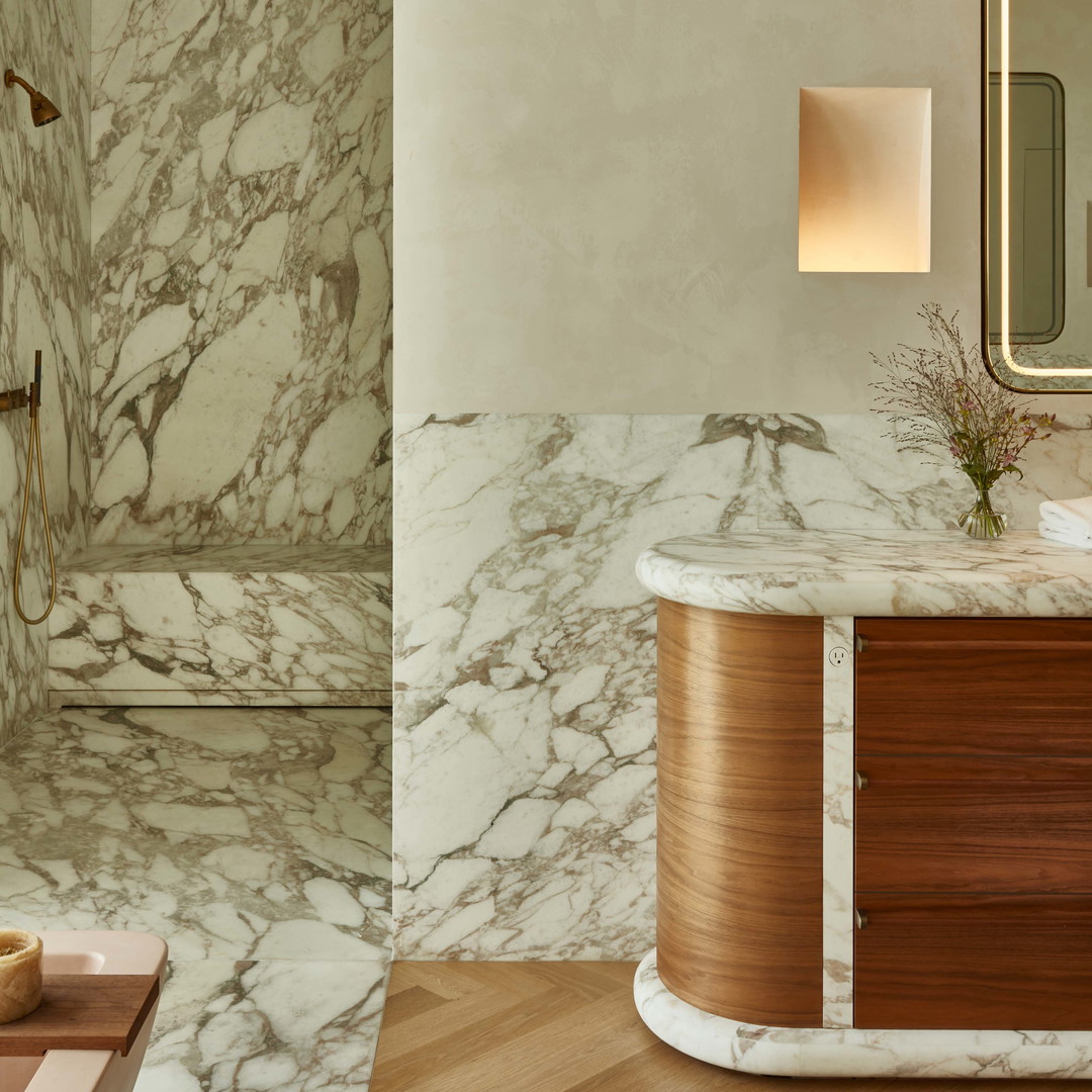 a bathroom with marble walls and a wooden counter