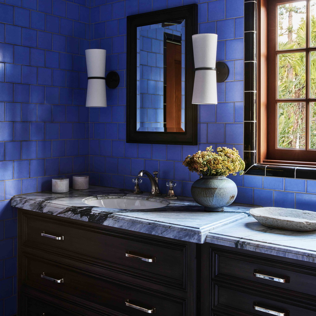 a blue bathroom with two sinks and a large mirror